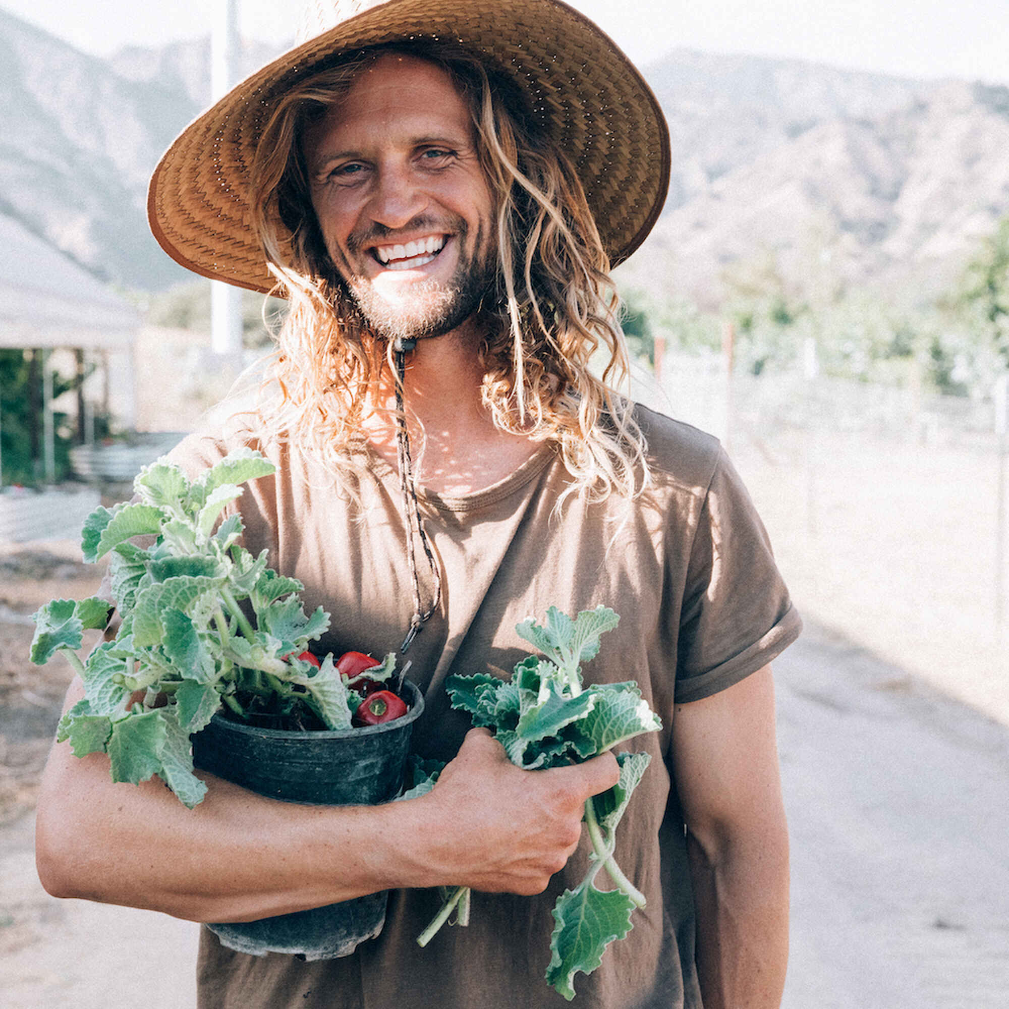 Greg Reese holding a potted tomato plant in a farm greenhouse