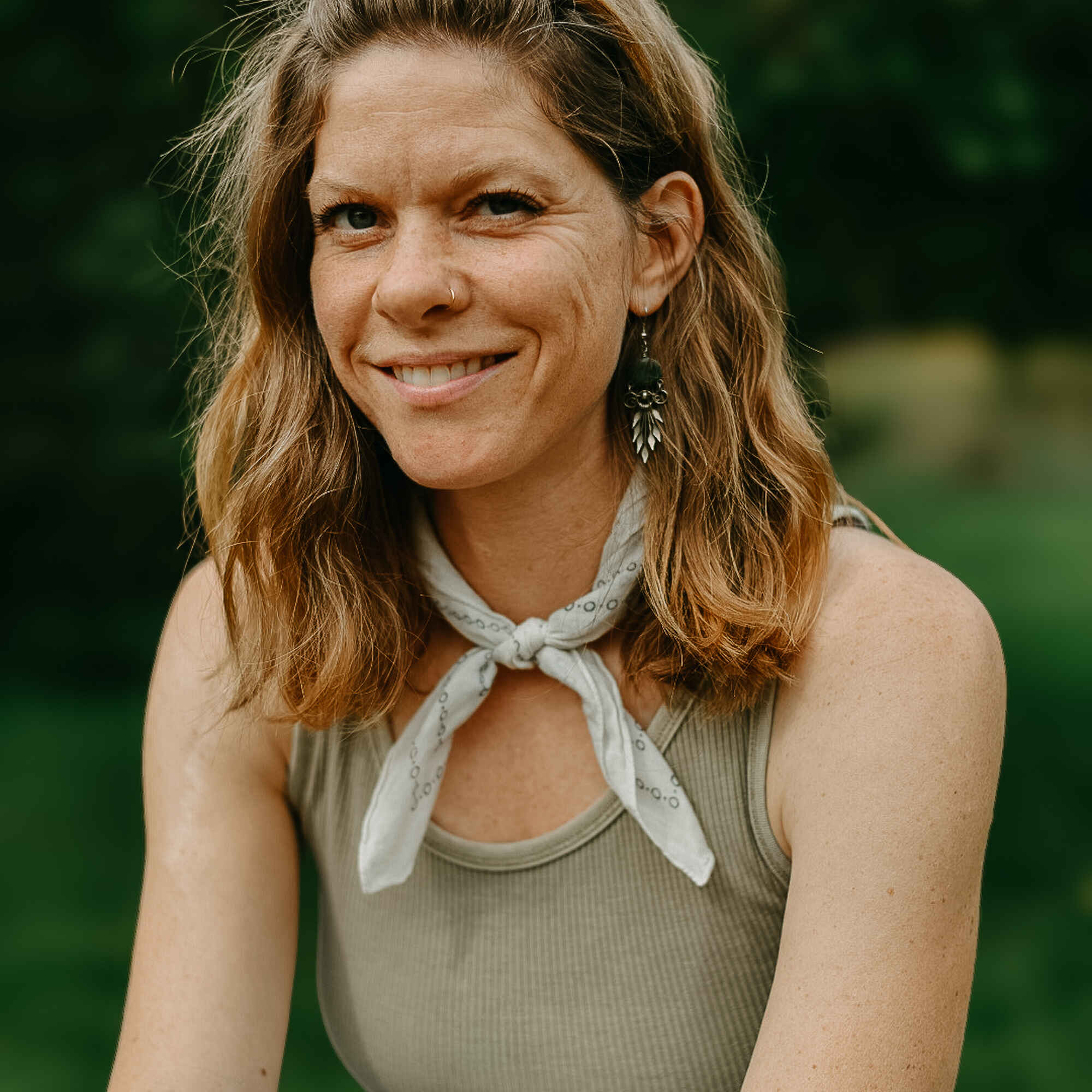 Holly Morgan, a team member at Farmer's Footprint, smiling outdoors with a blurred green background