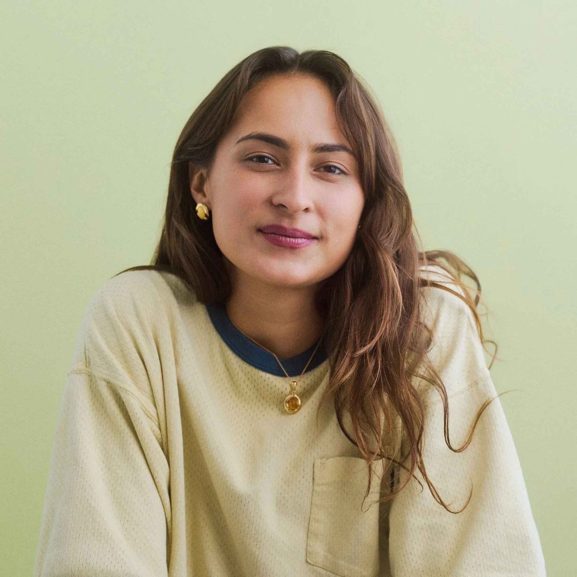 Isabela Zawistowska, smiling at the camera against a pale green background