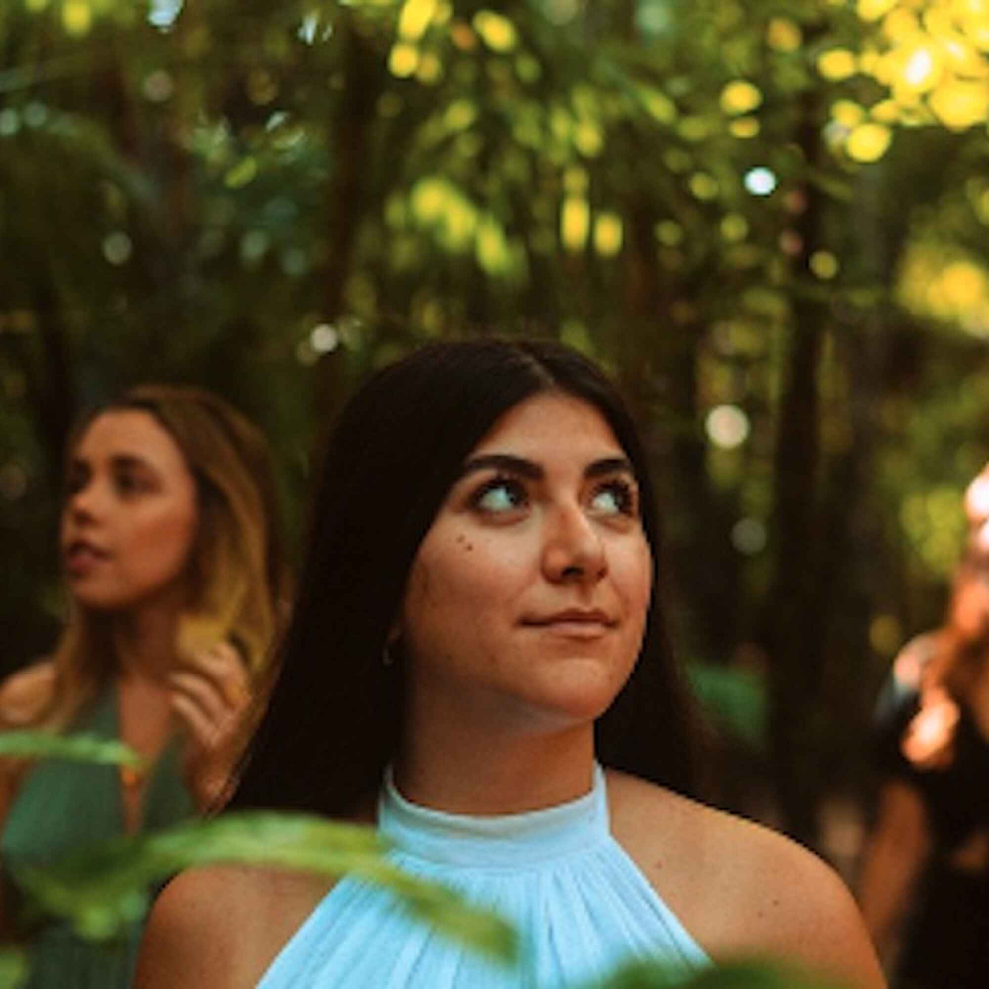 Mujer con top azul claro mirando hacia arriba en un entorno natural al aire libre