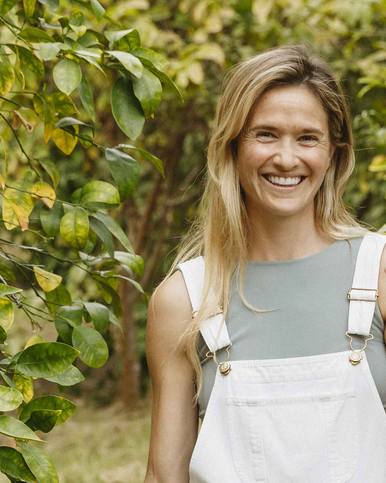Sarah Bourke Kettler smiling in a garden wearing white overalls