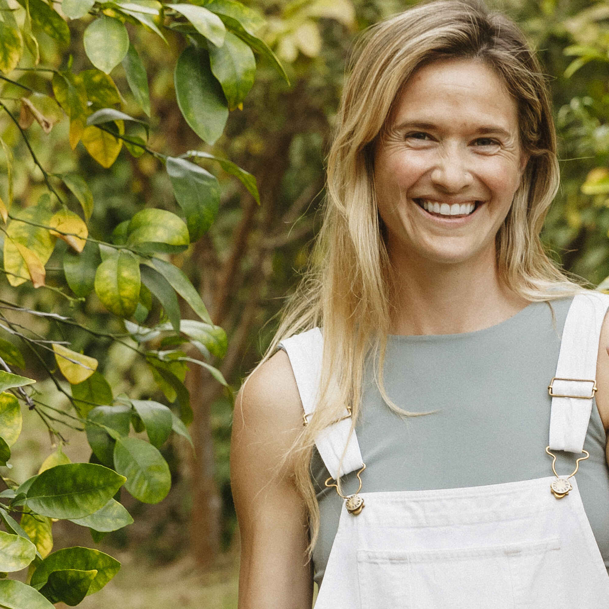 Sarah Bourke Kettler smiling in a garden wearing white overalls