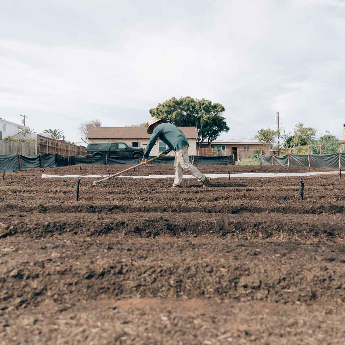 Person using a rake to shape and level soil in a raised garden bed