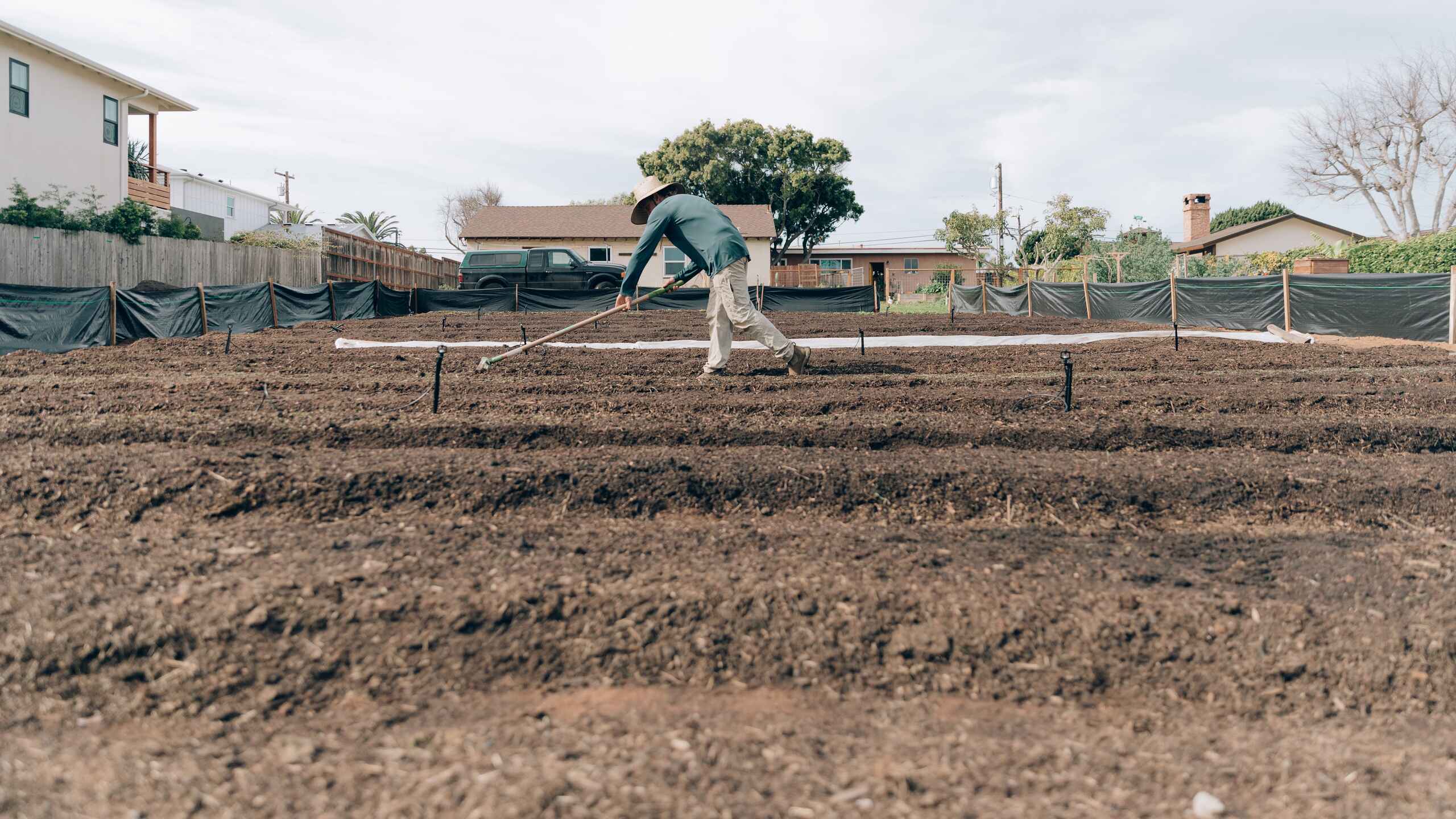 Person using a rake to shape and level soil in a raised garden bed