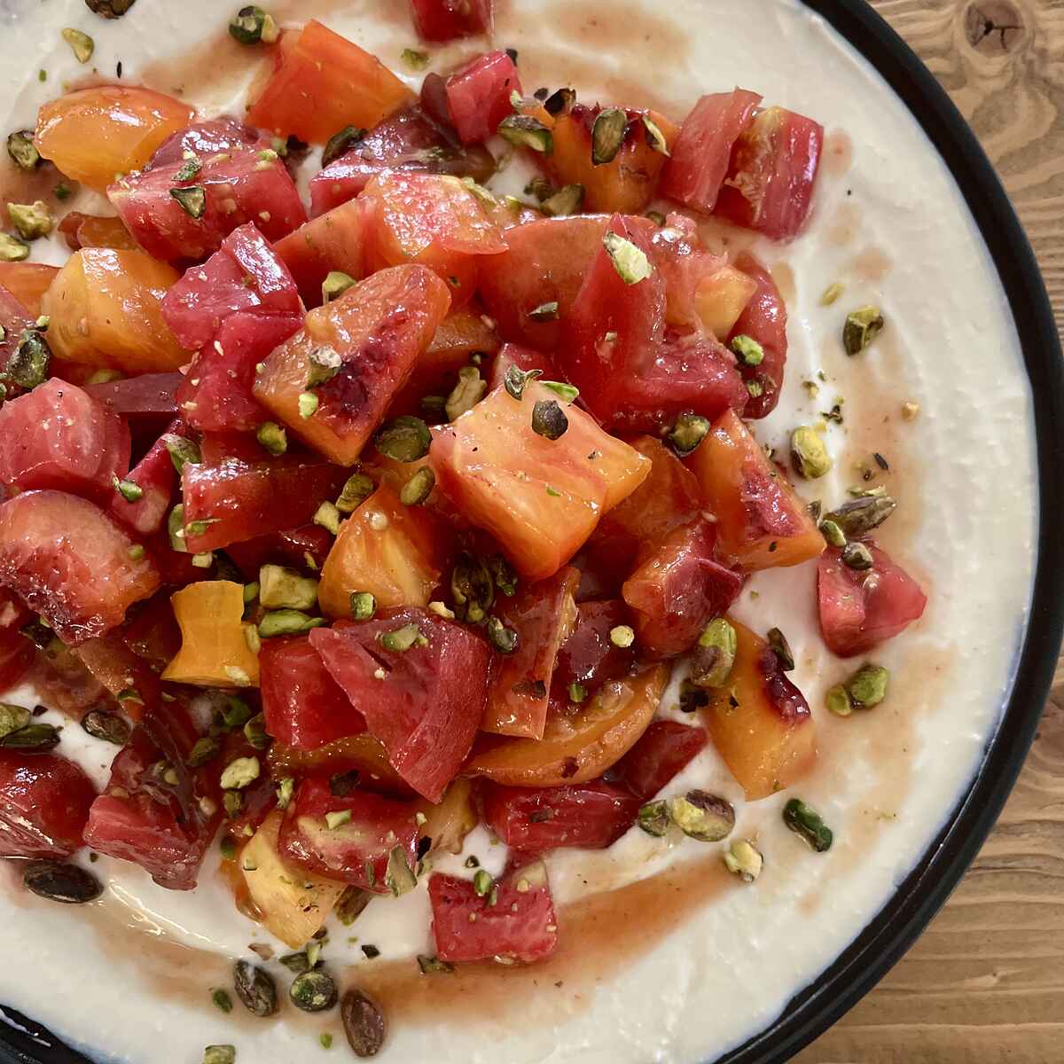 Caramelized peach and heirloom tomato salad served on whipped feta, garnished with pistachios