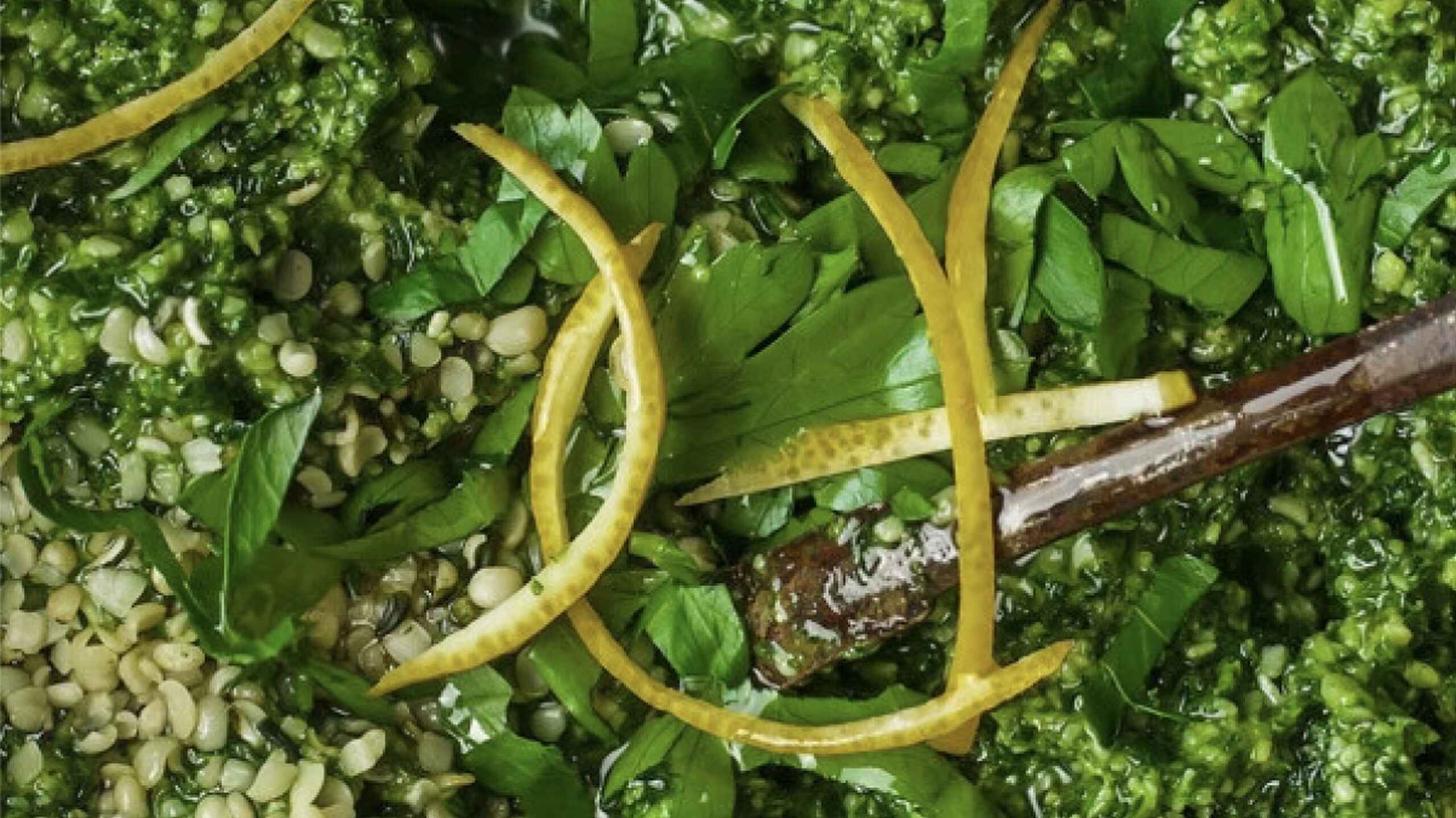 Pesto de c&aacute;&ntilde;amo con albahaca fresca y ralladura de lim&oacute;n en un recipiente de madera