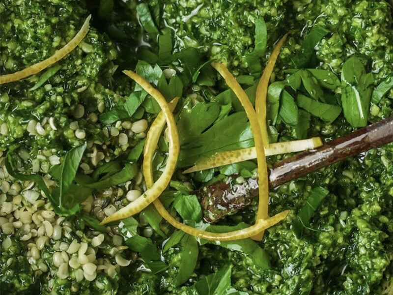 Pesto de c&aacute;&ntilde;amo con albahaca fresca y ralladura de lim&oacute;n en un recipiente de madera