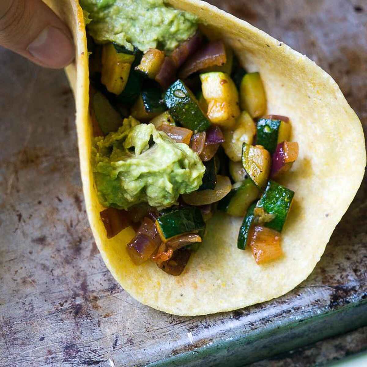 Calabacita amarilla y calabac&iacute;n frescos rebanados sobre una superficie de madera con tomates cherry y lechuga para preparar tacos de calabacita