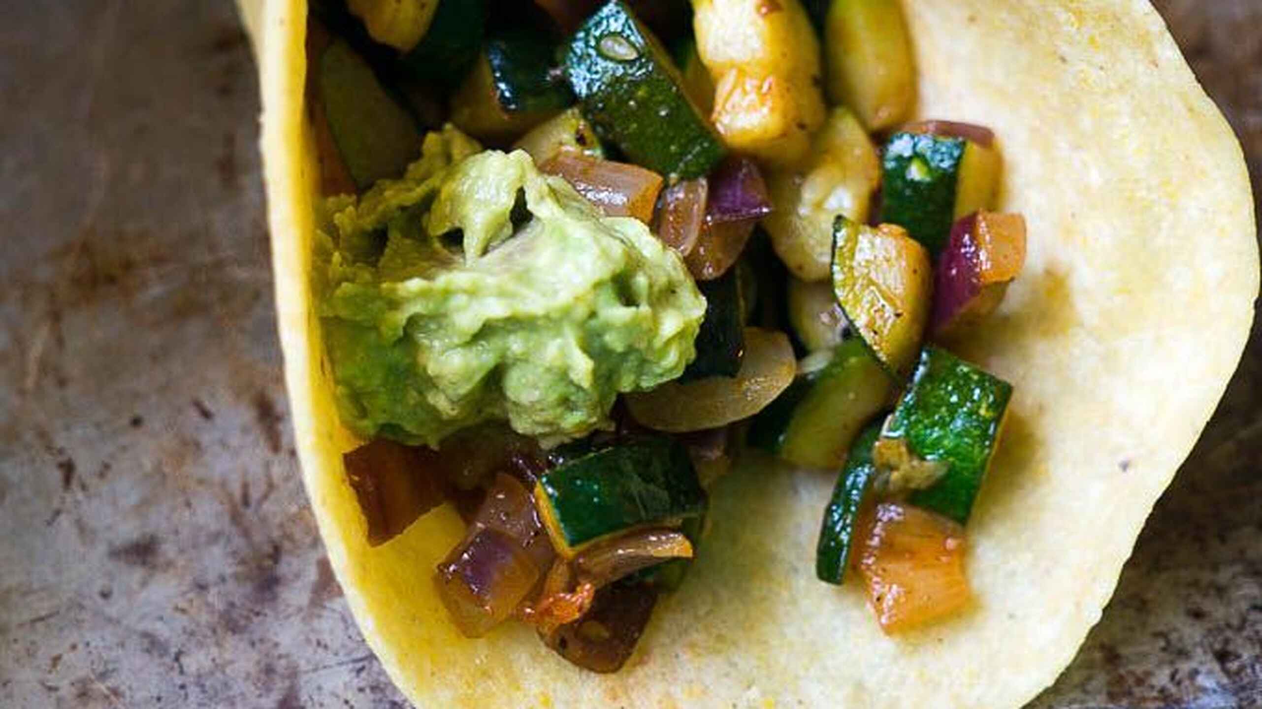 Calabacita amarilla y calabac&iacute;n frescos rebanados sobre una superficie de madera con tomates cherry y lechuga para preparar tacos de calabacita