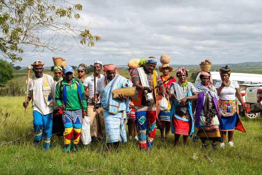 Grupo de agricultores con vestimenta tradicional y colorida de pie juntos en un campo rural