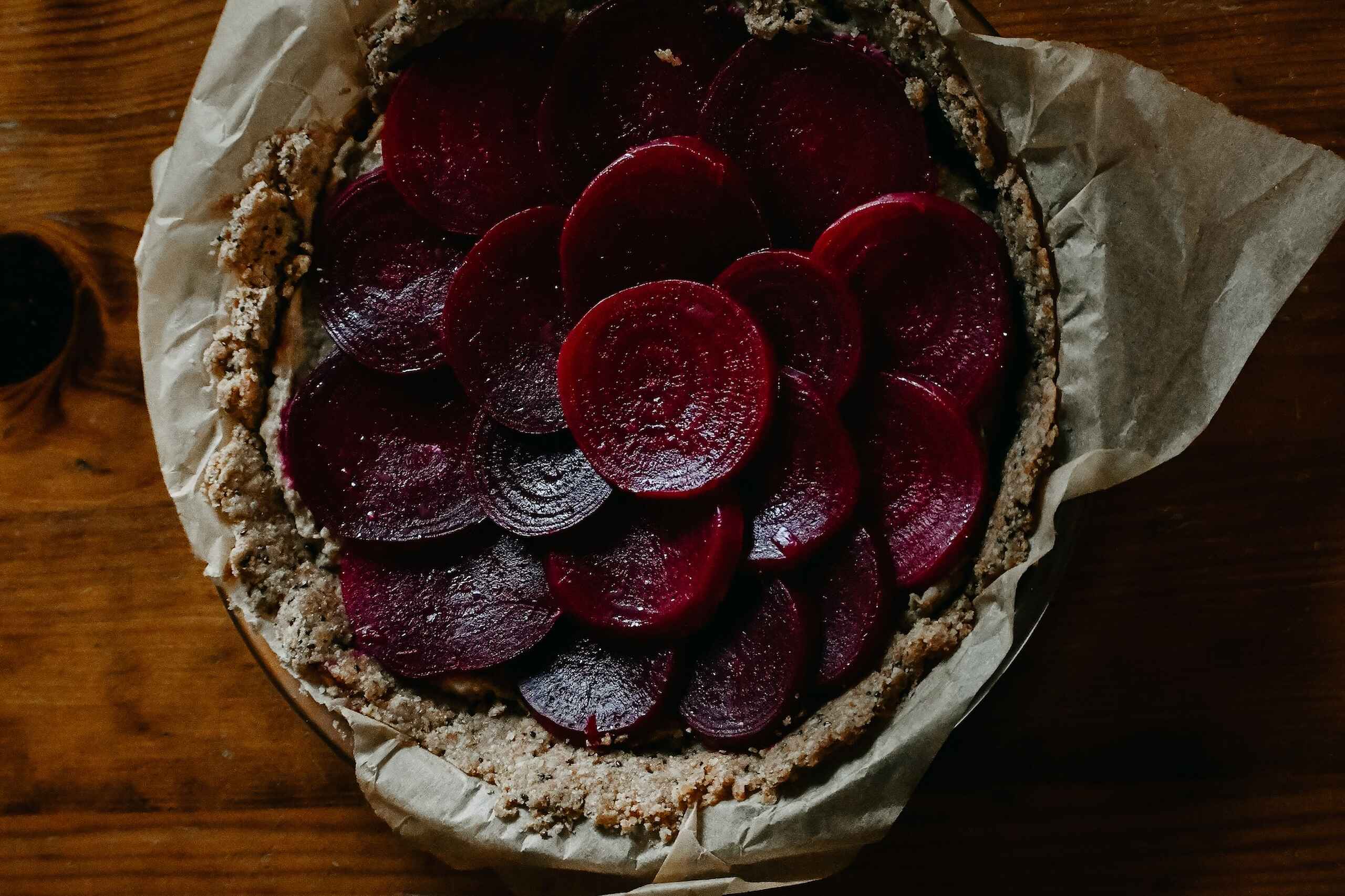 Beet and grain tart with thinly sliced roasted beets arranged on a rustic crust