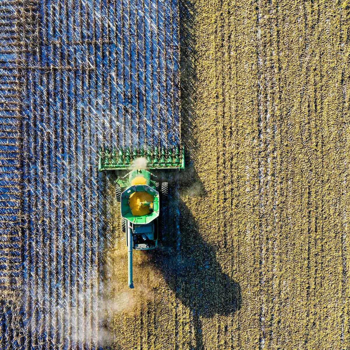 Aerial view of a combine harvester working across fields of different crops