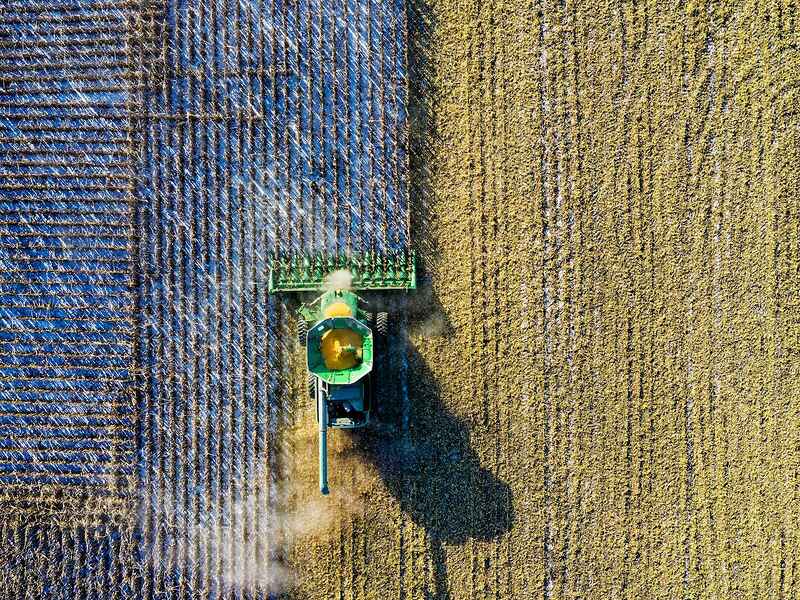 Aerial view of a combine harvester working across fields of different crops