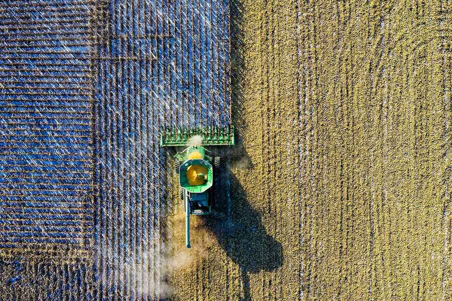 Aerial view of a combine harvester working across fields of different crops