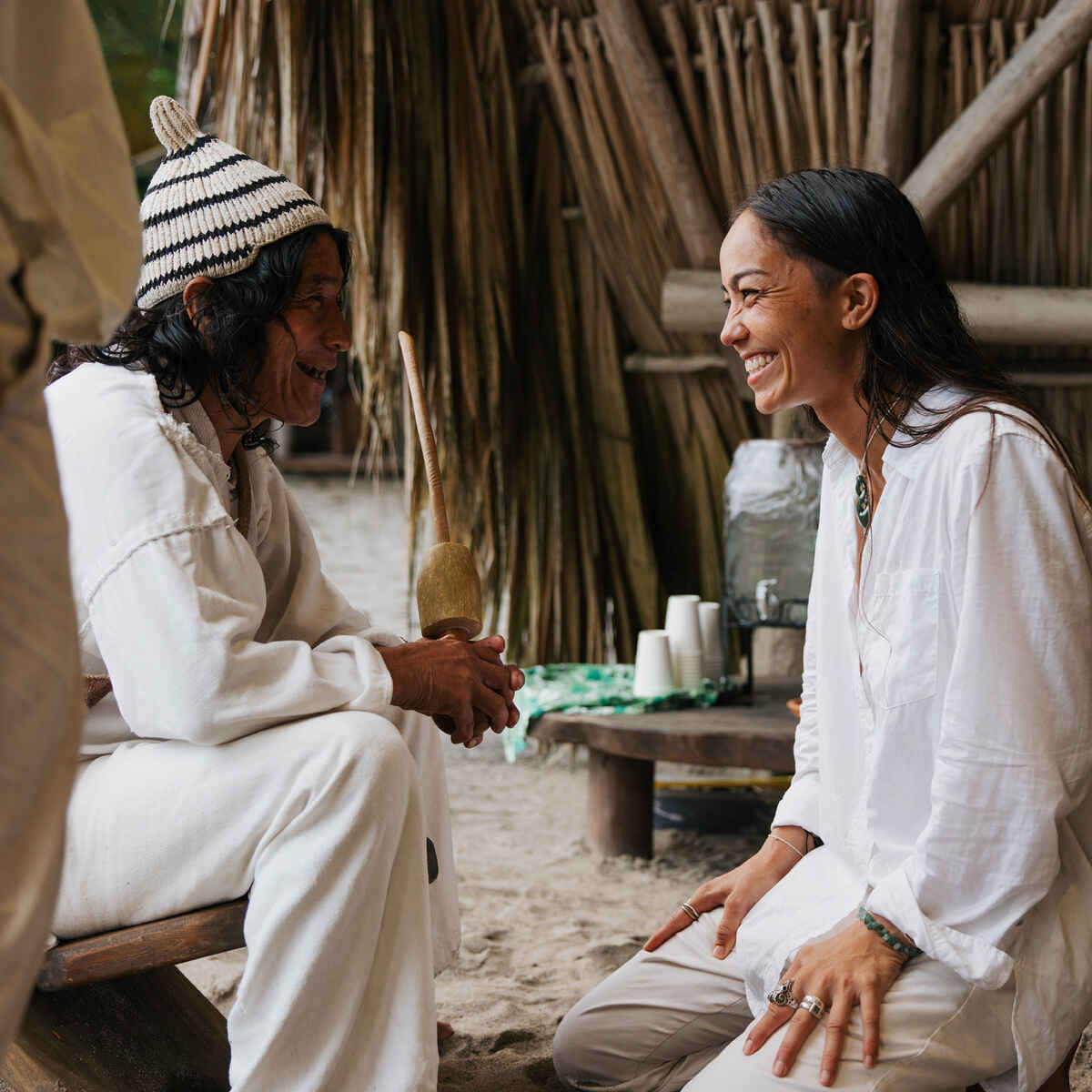 Indigenous elder and woman sharing a warm conversation in a traditional village setting