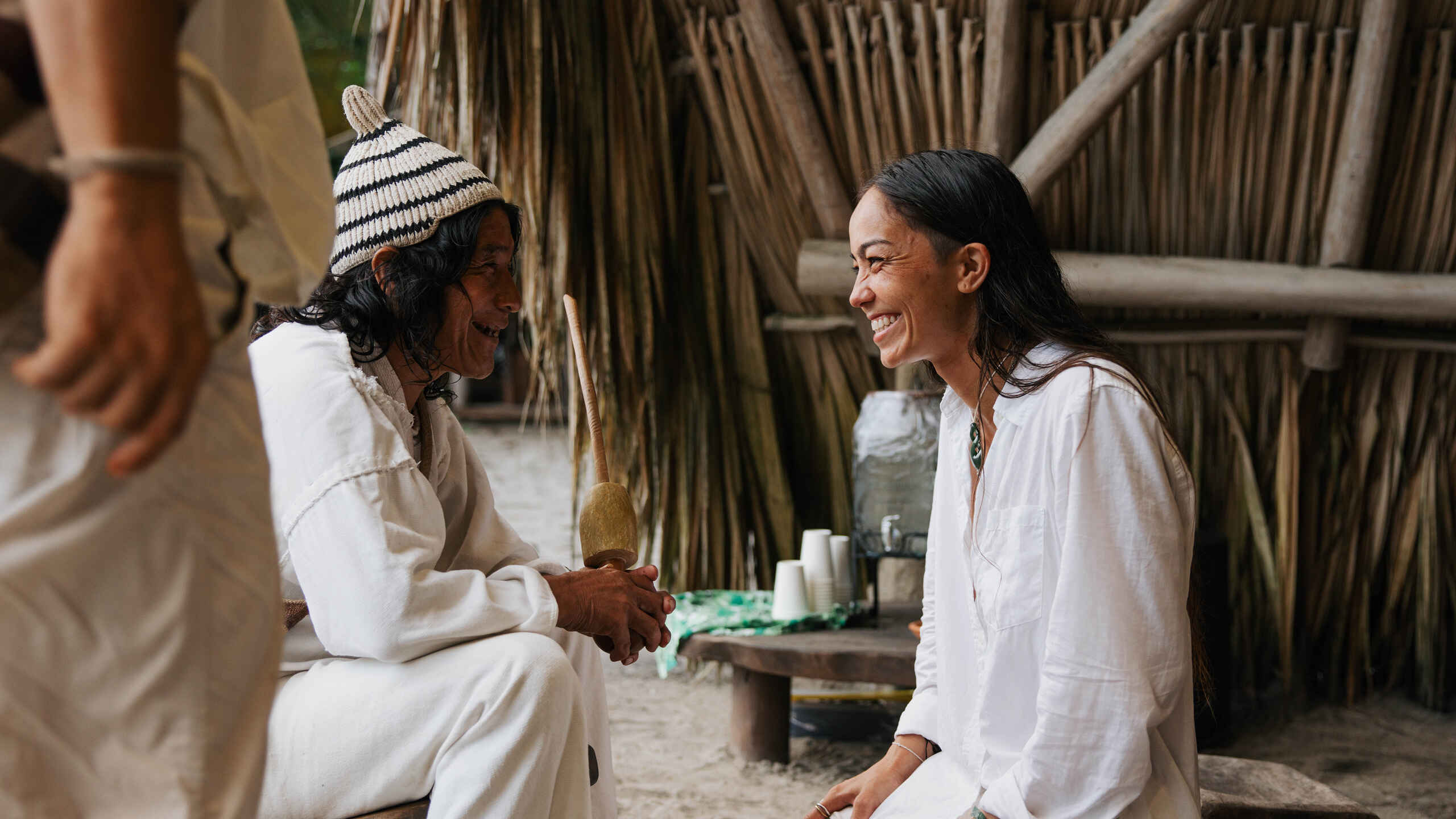 Indigenous elder and woman sharing a warm conversation in a traditional village setting