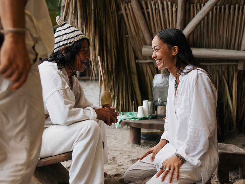 Indigenous elder and woman sharing a warm conversation in a traditional village setting