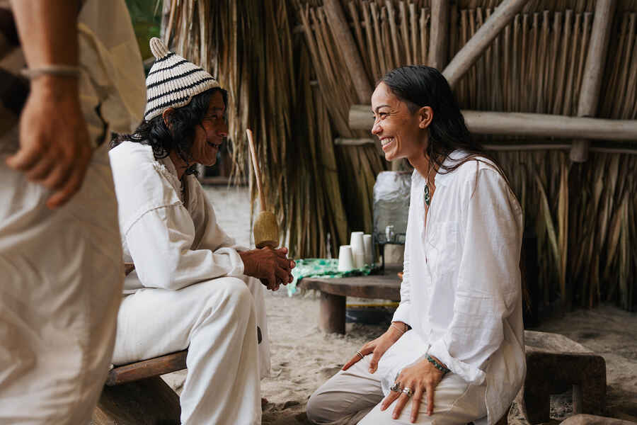 Indigenous elder and woman sharing a warm conversation in a traditional village setting