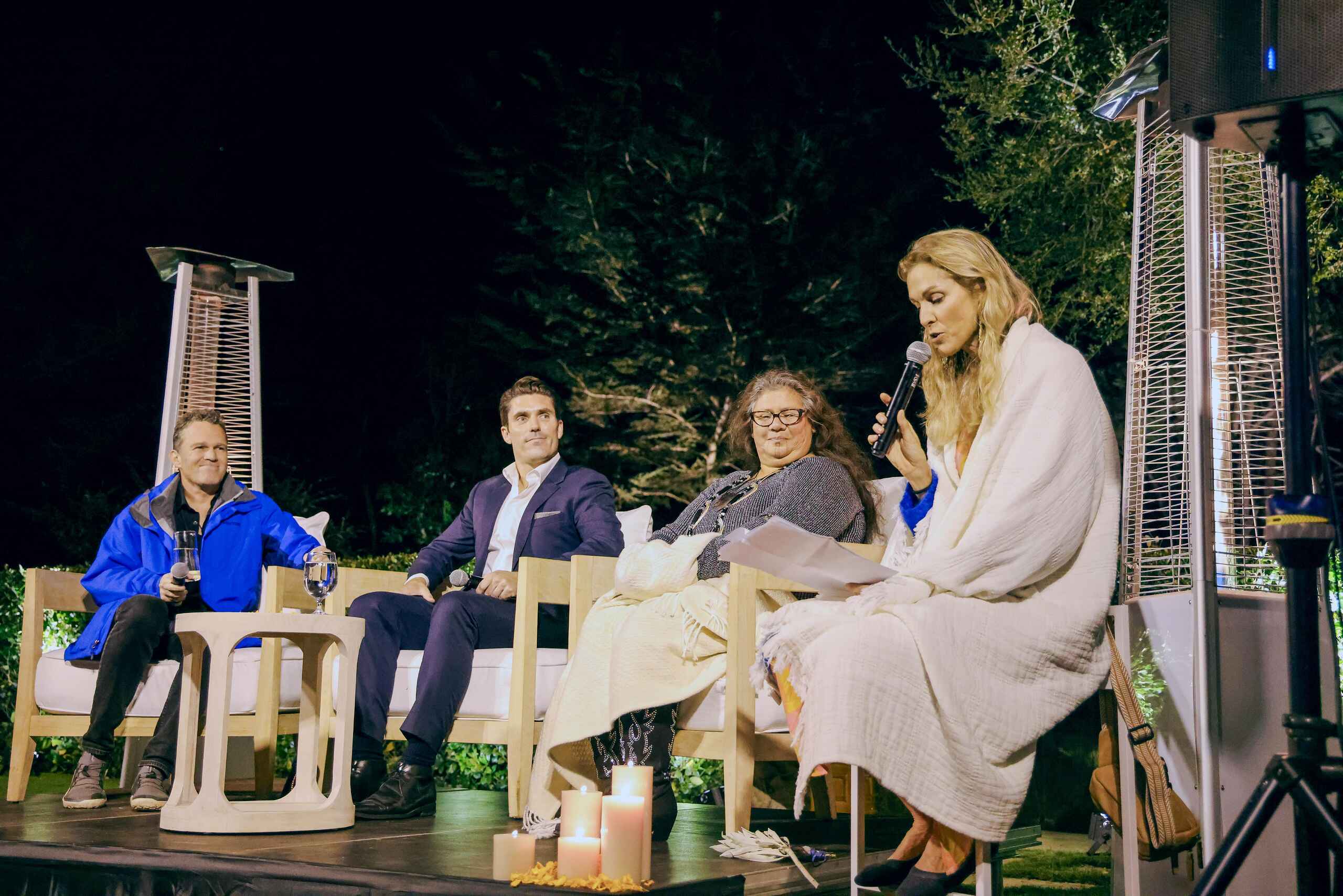 Panel discussion on stage with four seated participants and a moderator holding a microphone