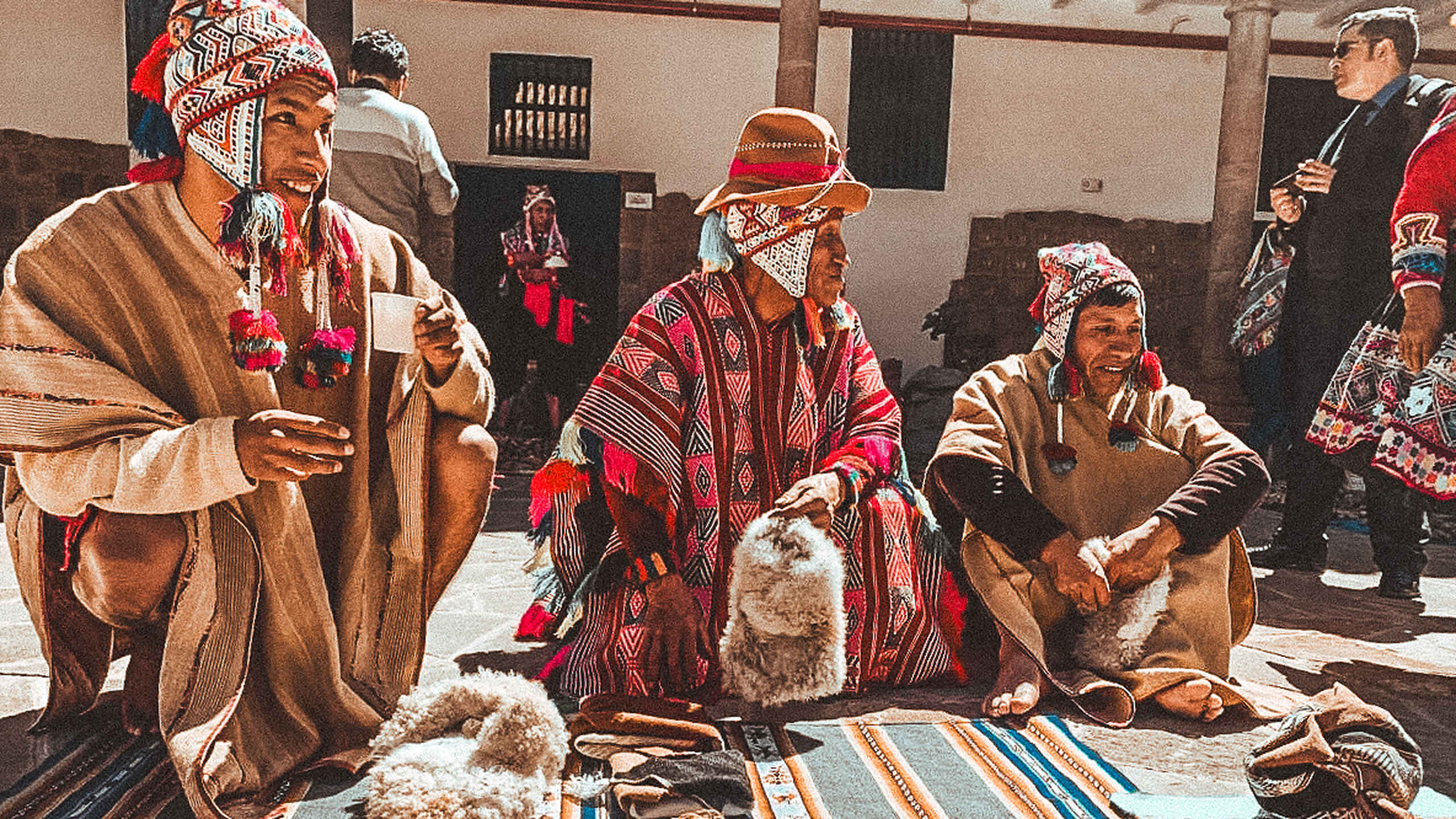 Andean community members in traditional dress and textiles demonstrate ancestral weaving practices during a cultural gathering