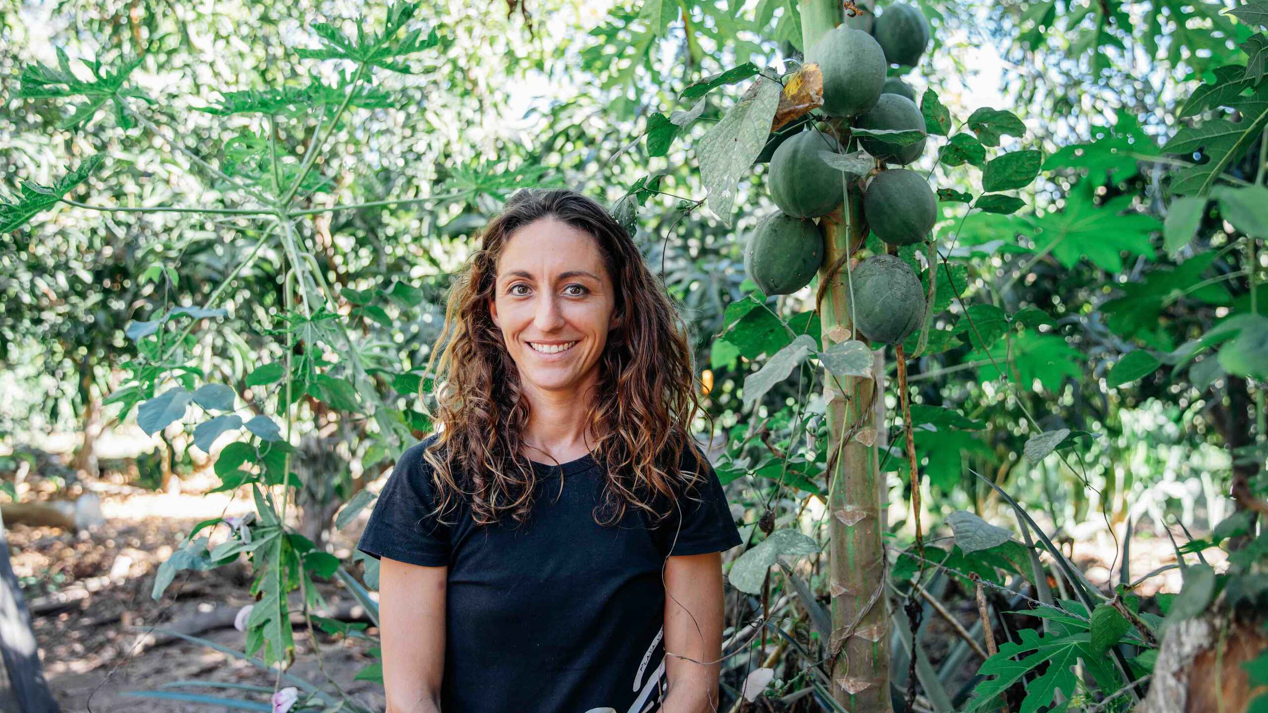 Amanda Harris stands among mango trees in an orchard