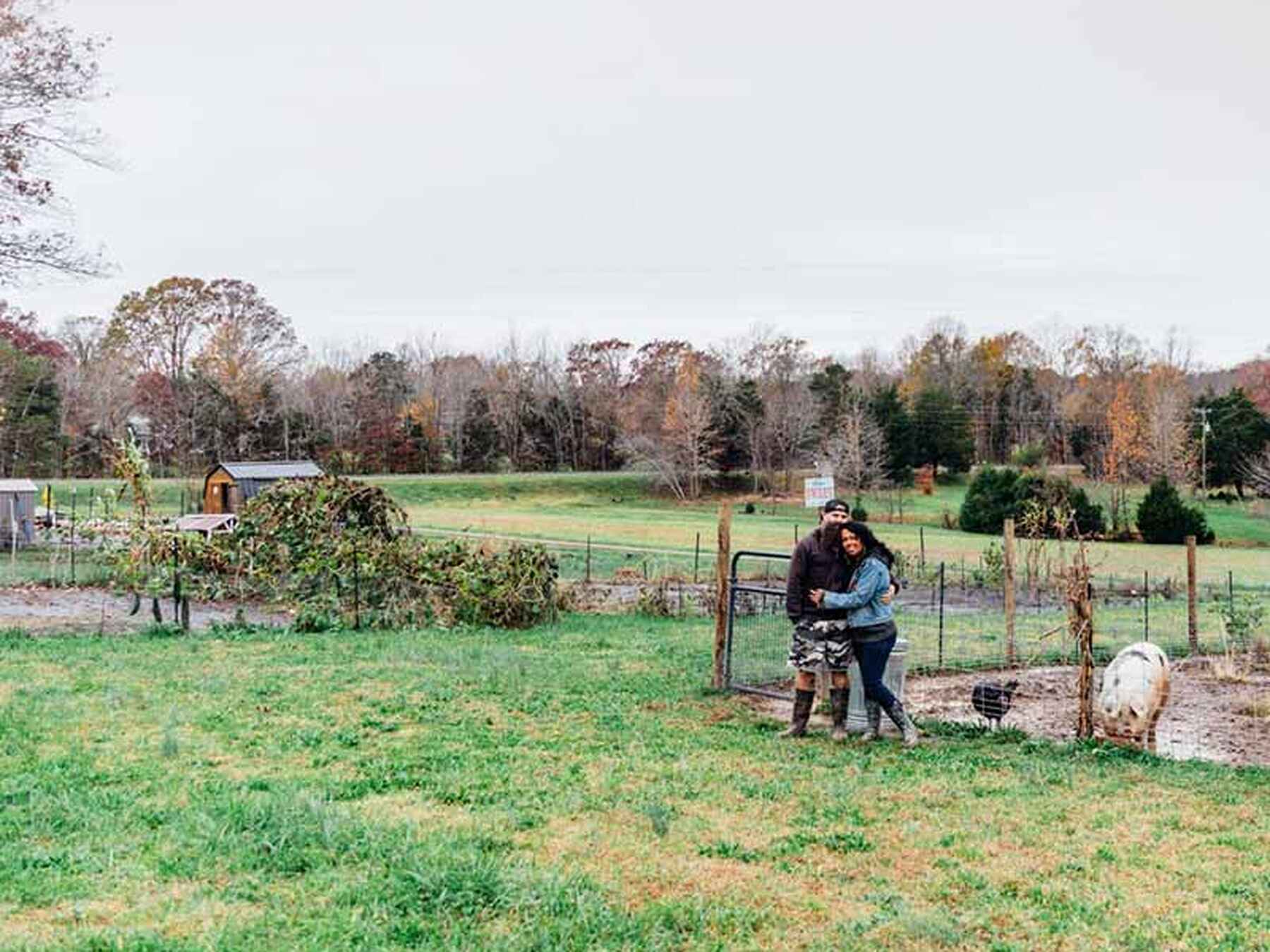 Couple embracing in a fenced garden area on their farm during autumn
