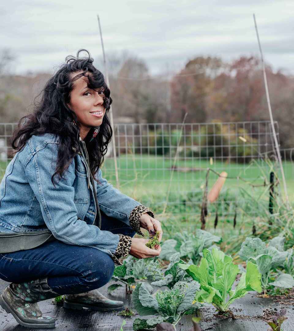 Woman harvesting fresh greens from a vegetable garden bed