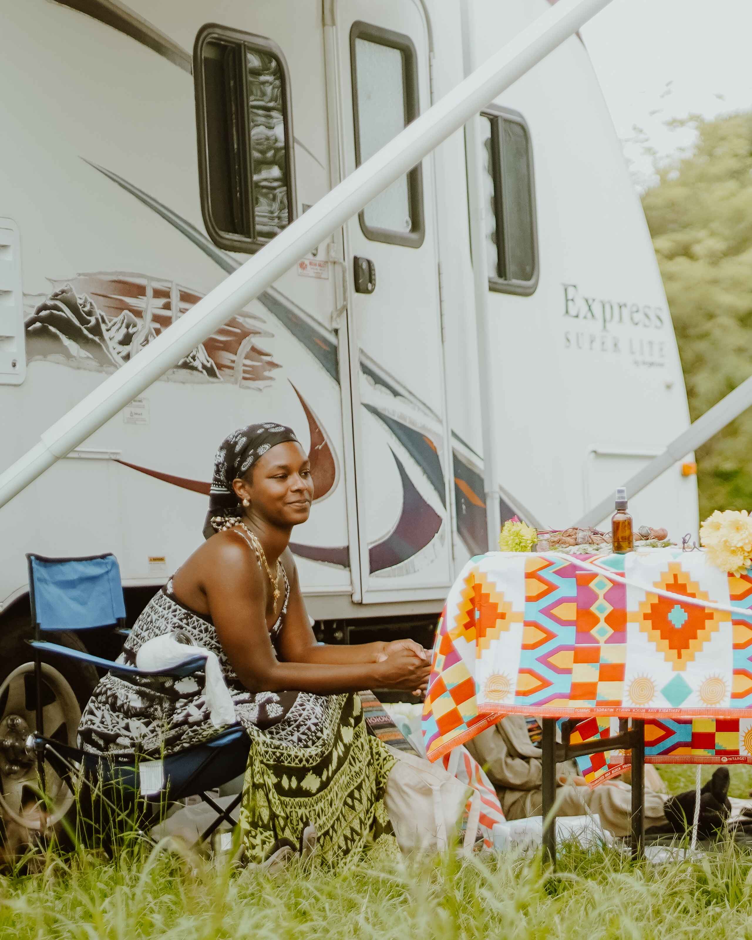 Woman sits at a table outside an RV, preparing food for a community gathering