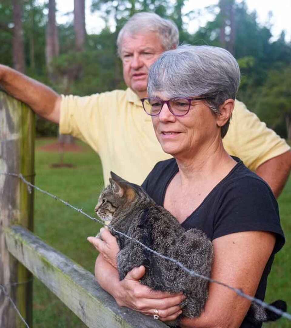 Deb Wray holds a young bobcat while Johnny Wray points toward the pasture on their farm