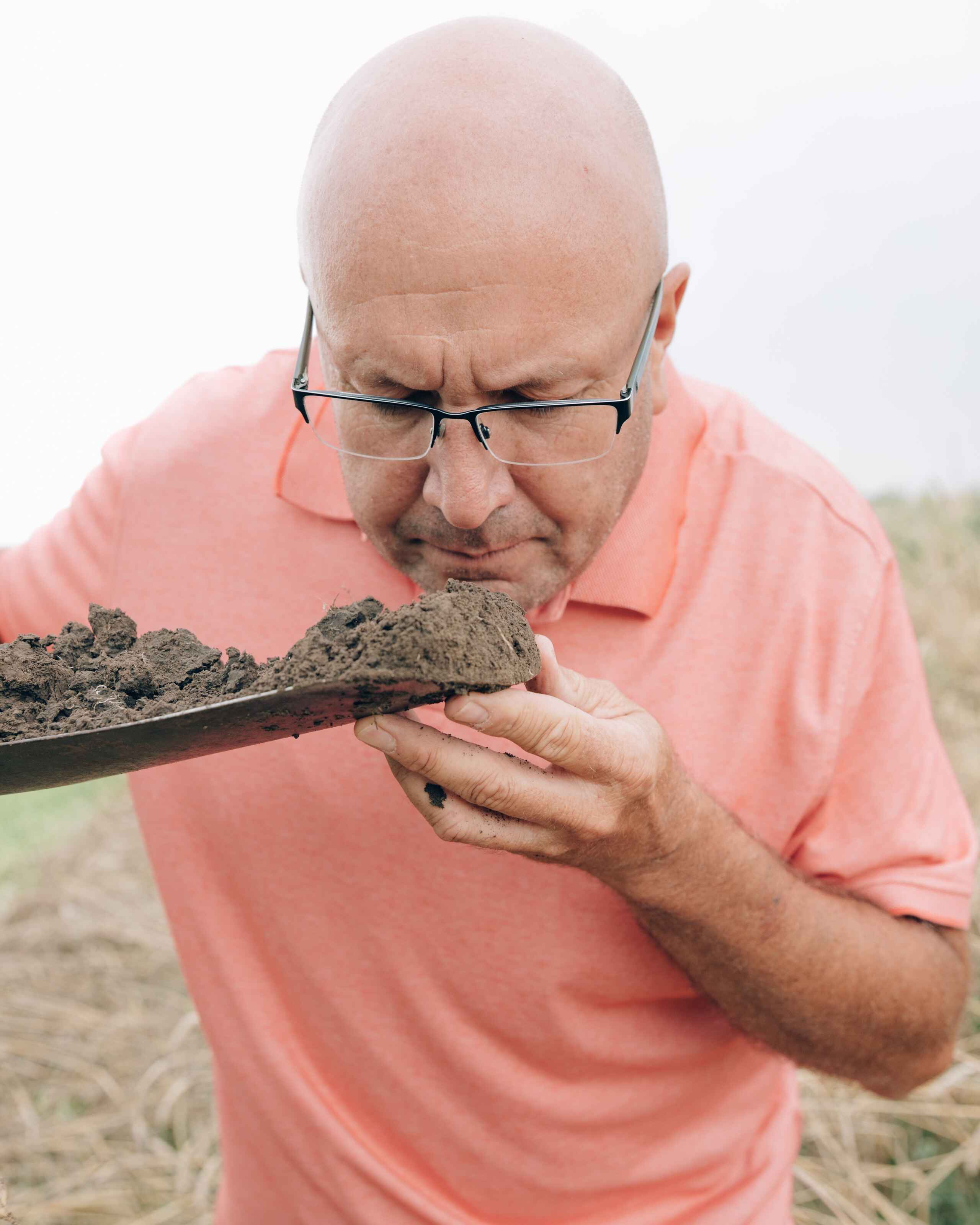 Del Ficke examines a soil sample in his hand while standing in a field