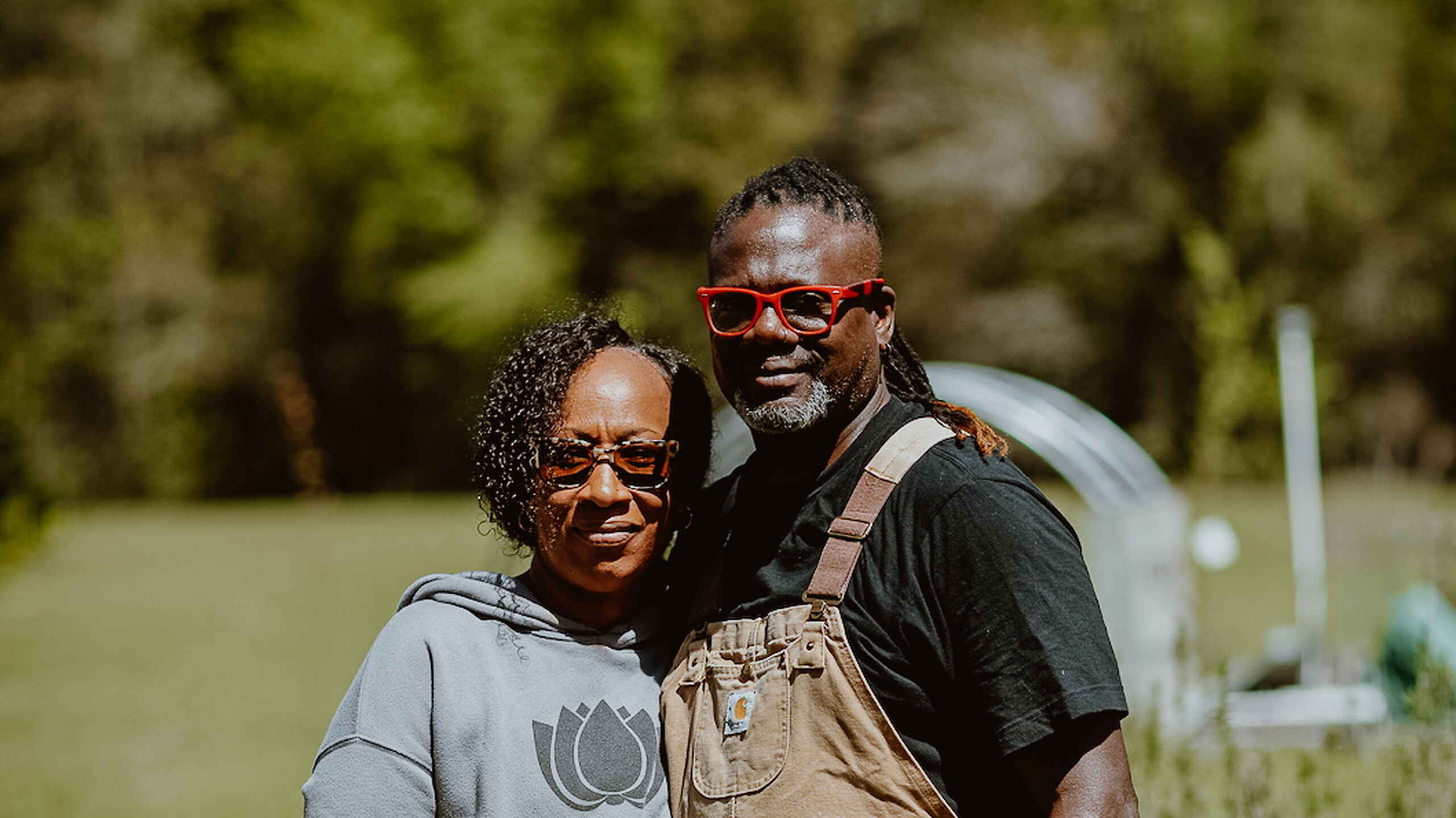 Two farmers wearing orange sunglasses smile together at Gilliard Farms