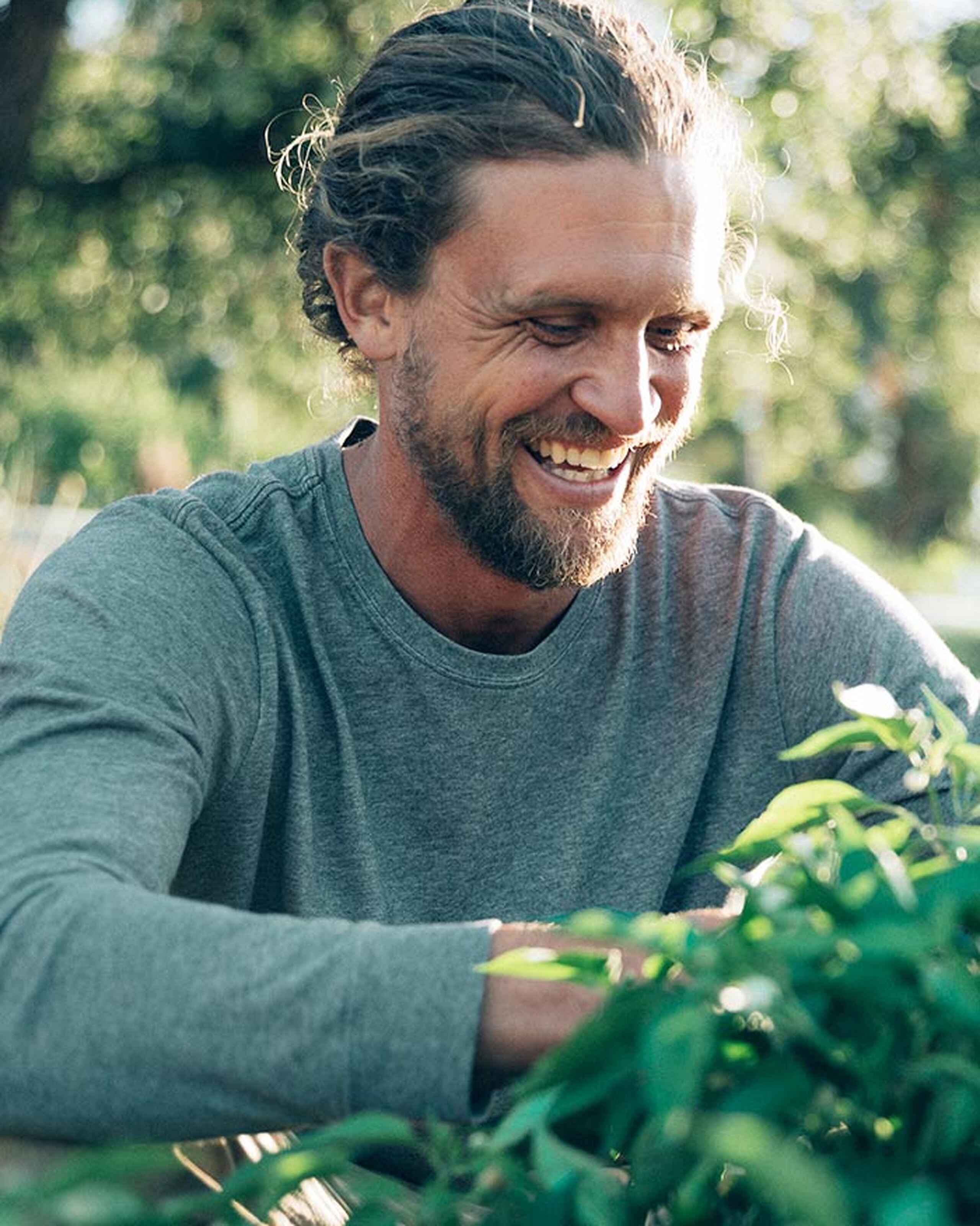 Greg Reese smiling while tending to plants in a garden