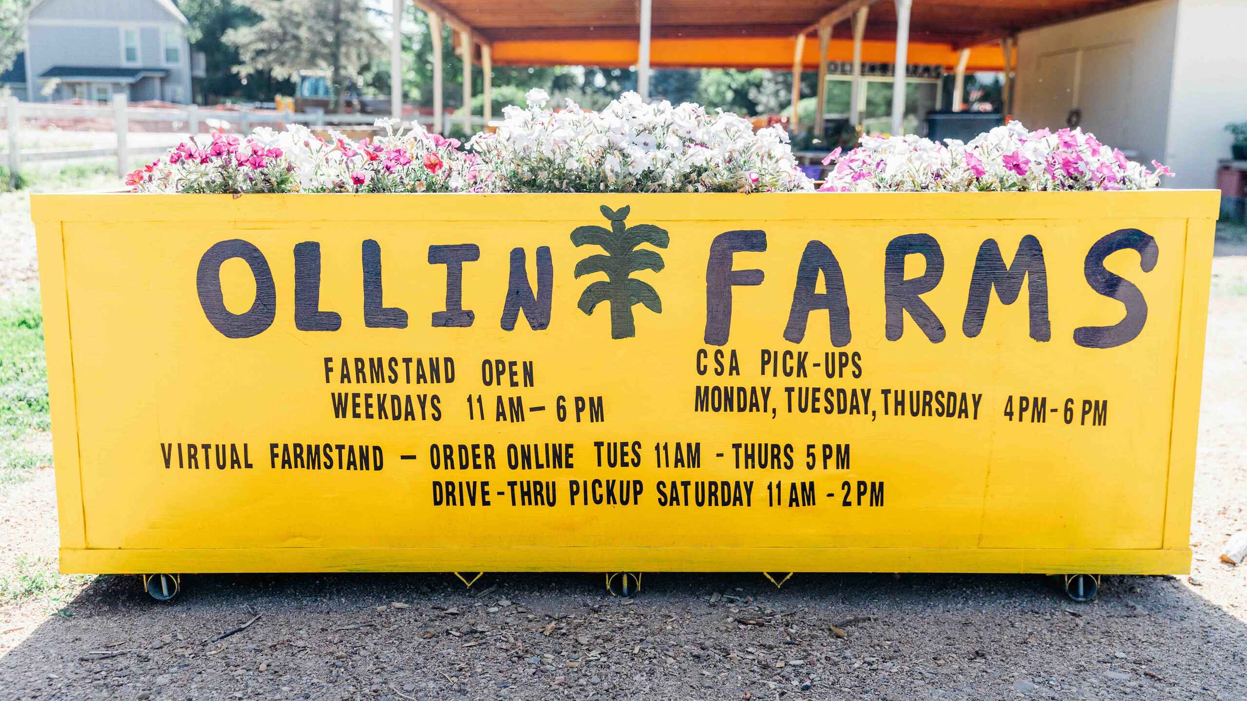 Ollin Farms farmstand sign displaying operating hours and CSA pickup information