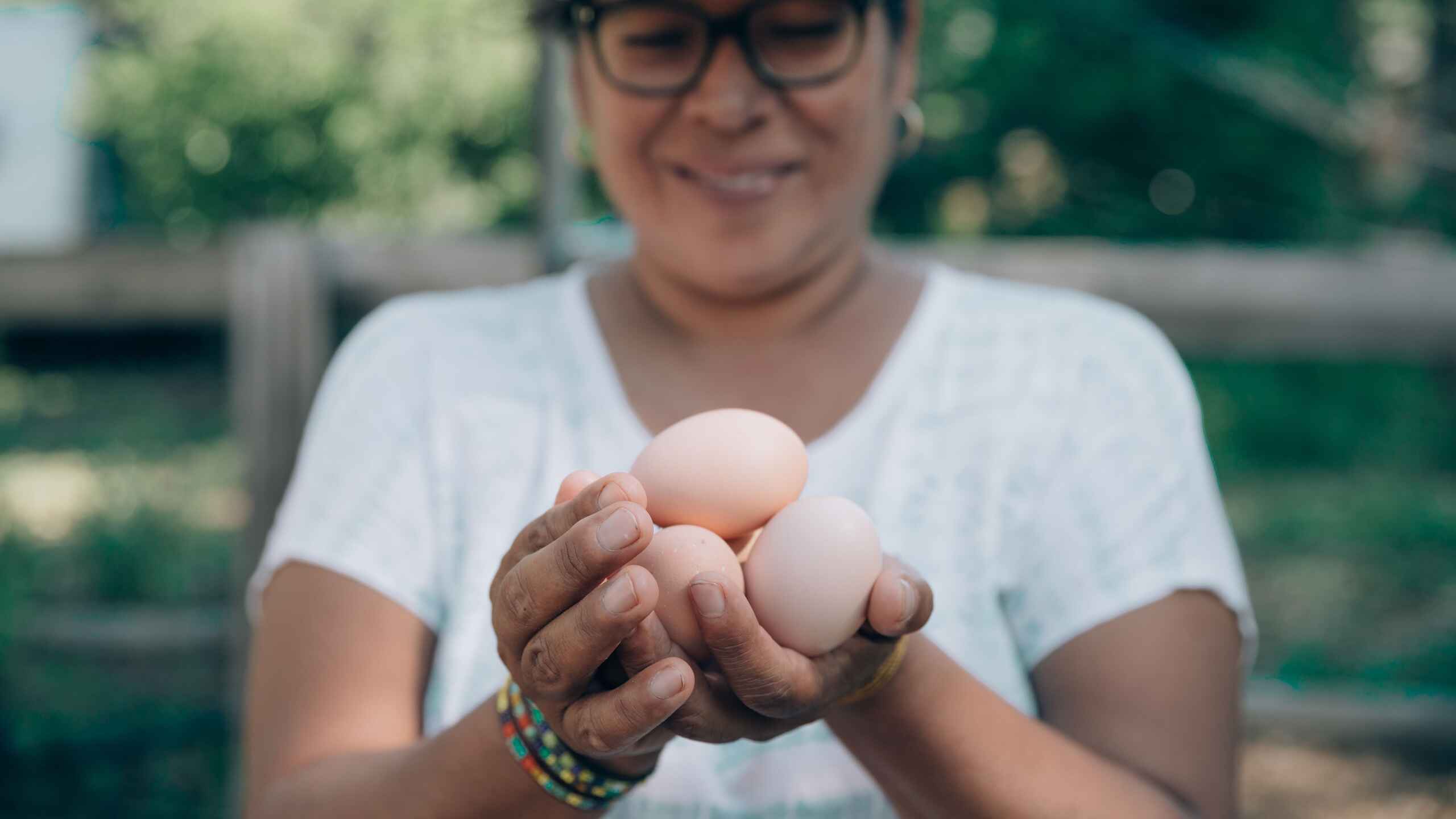 Woman holding three fresh eggs from her farm