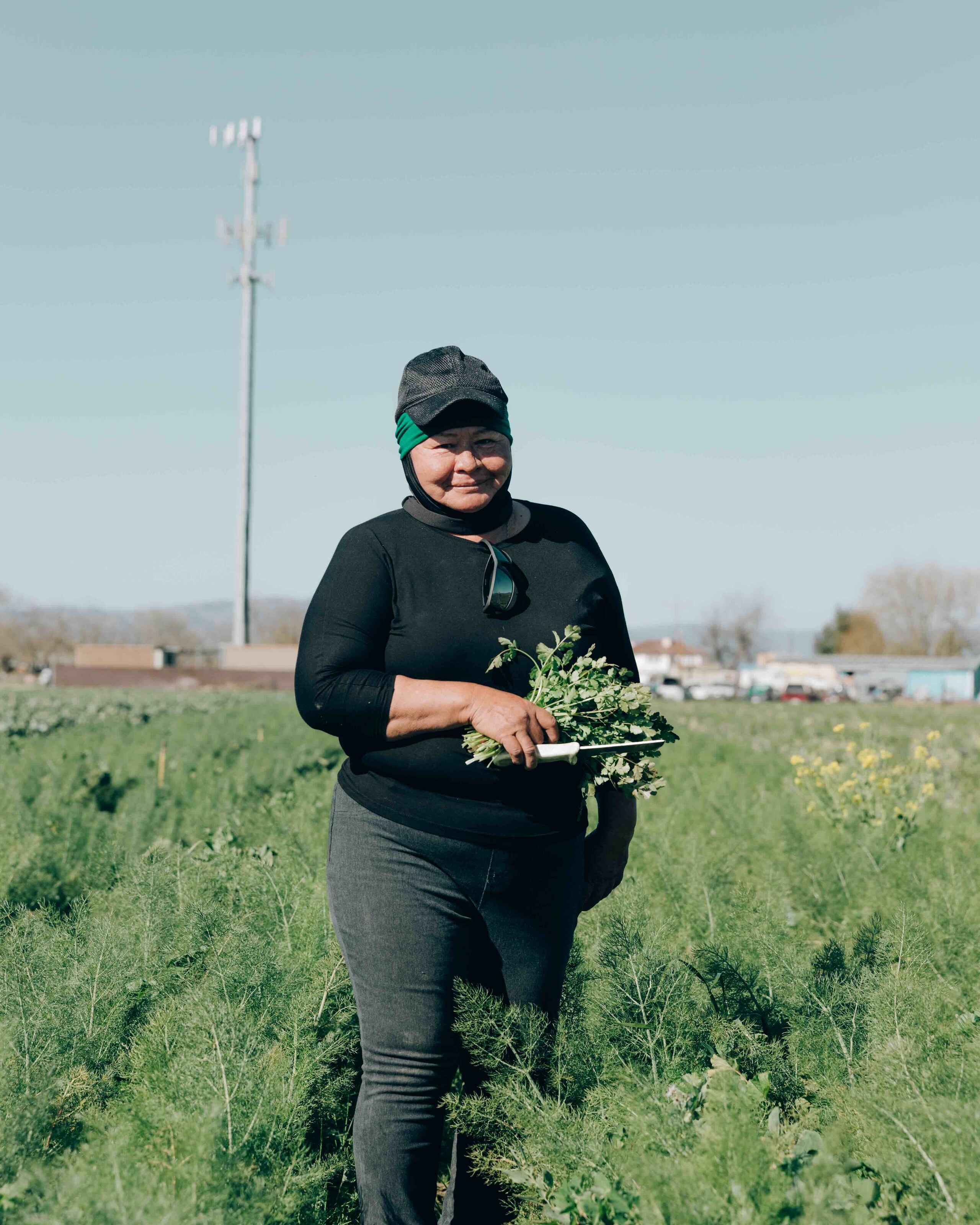 Maria Catal&aacute;n holds freshly harvested greens in a thriving vegetable field