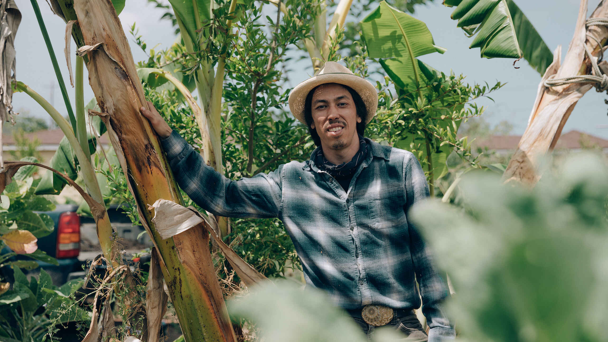 Farmer Nathan Lou stands with crops on his farm.
