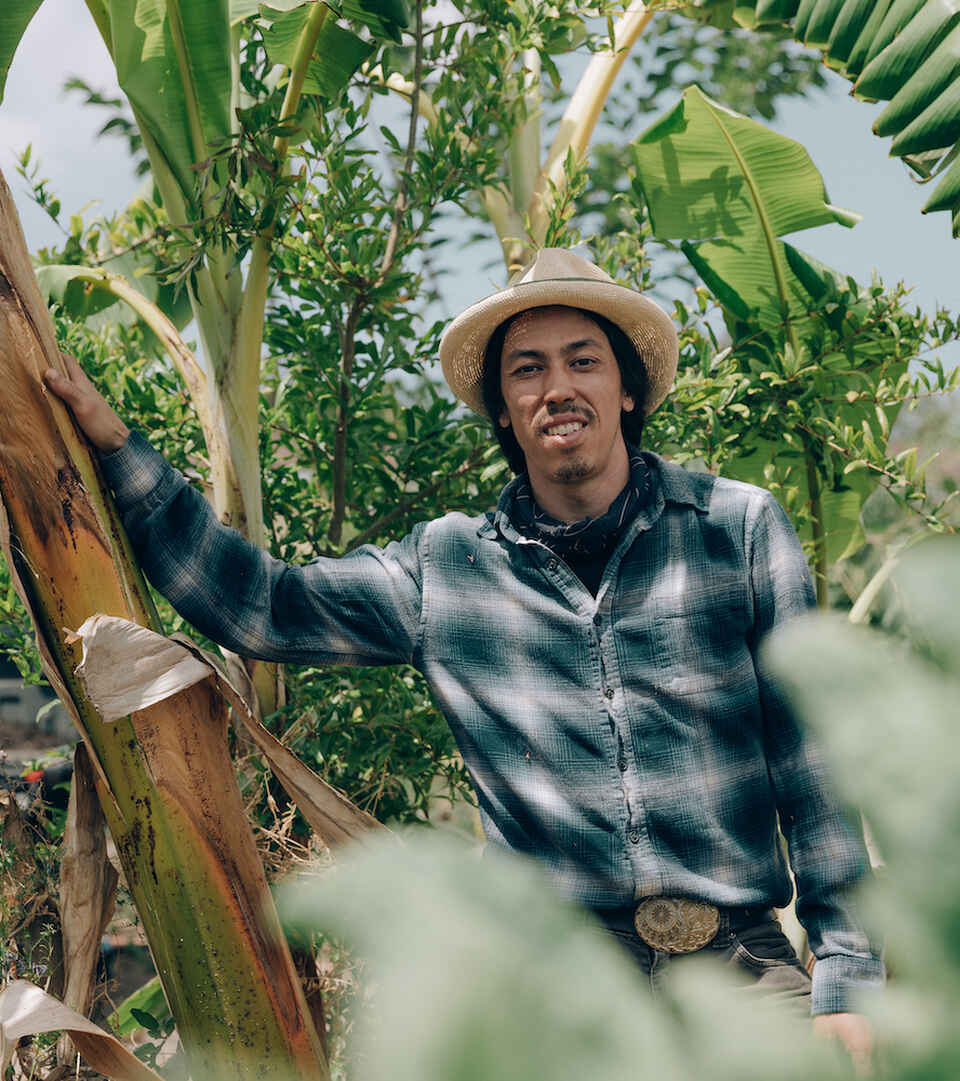 Farmer Nathan Lou stands with crops on his farm.