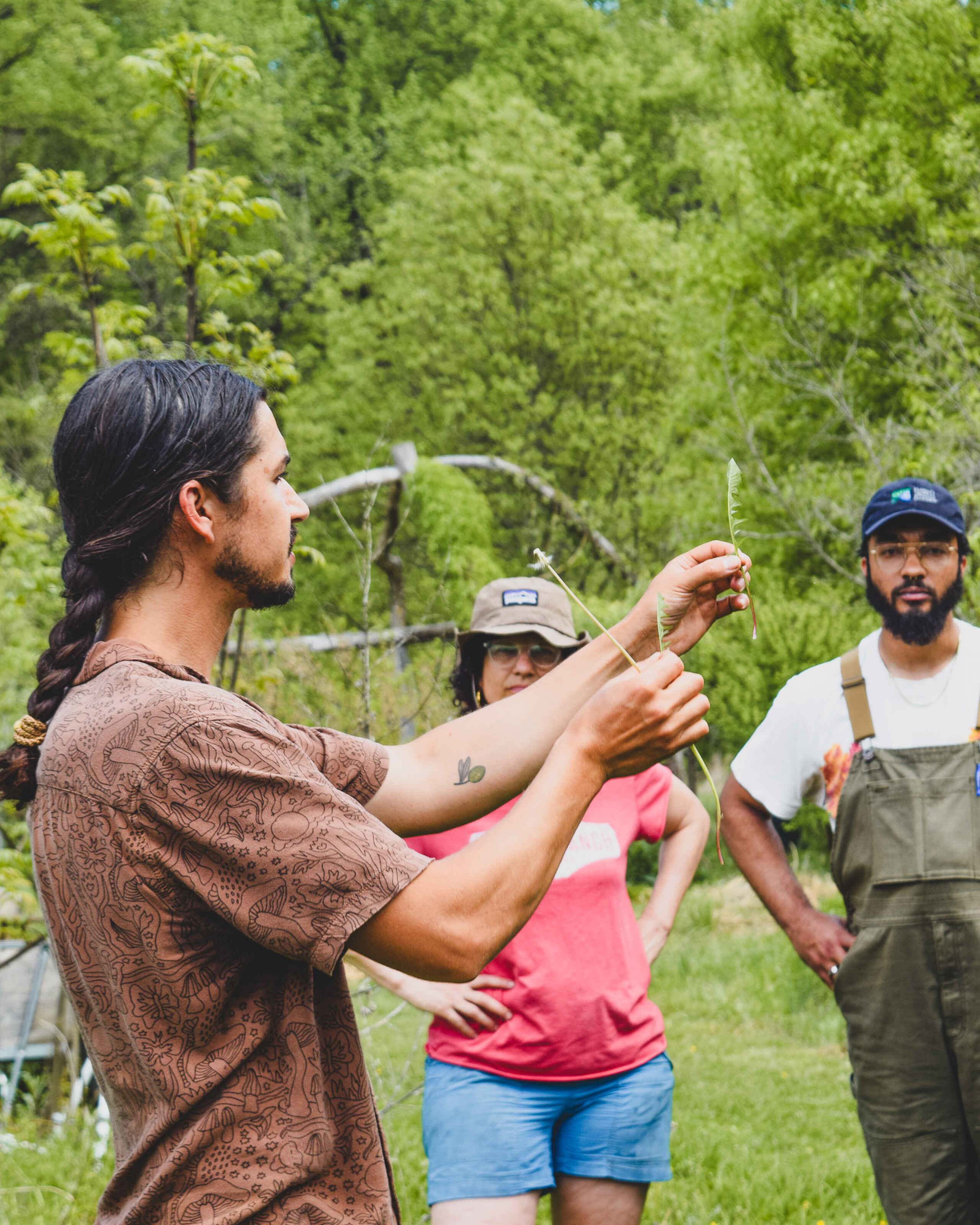 A forager instructor demonstrates mushroom identification techniques to a group of students in a forest setting