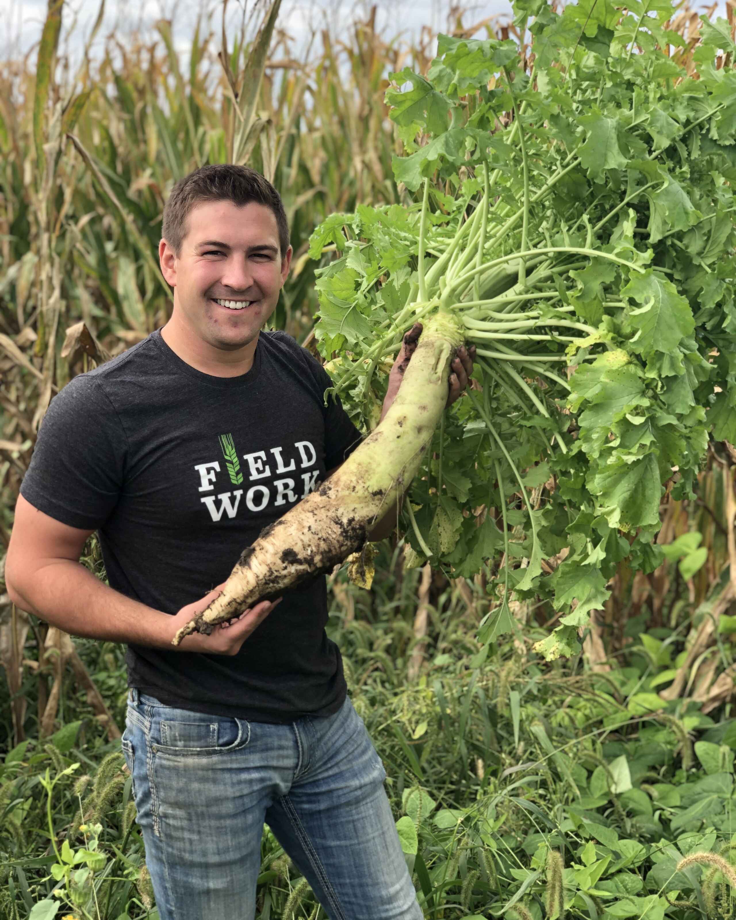 Mitchell Hora holds a freshly harvested parsnip in a cover crop field