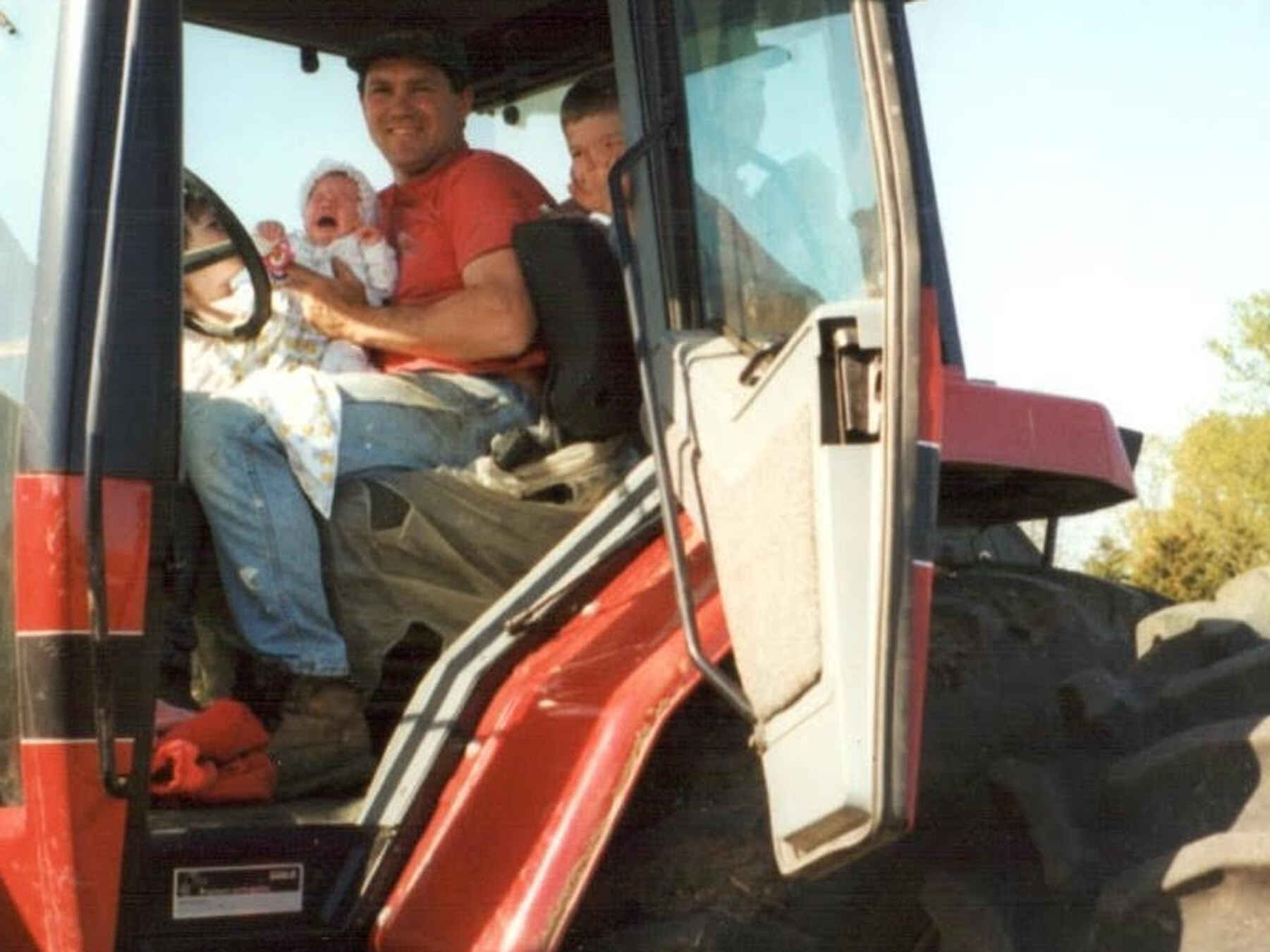 Mitchell Hora and his family sit in the cab of a large red farm tractor
