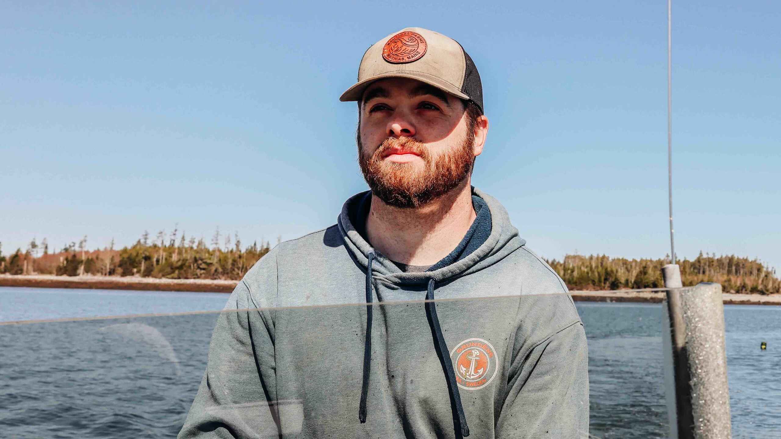 Man on a boat dock overlooking a calm lake surrounded by evergreen forest