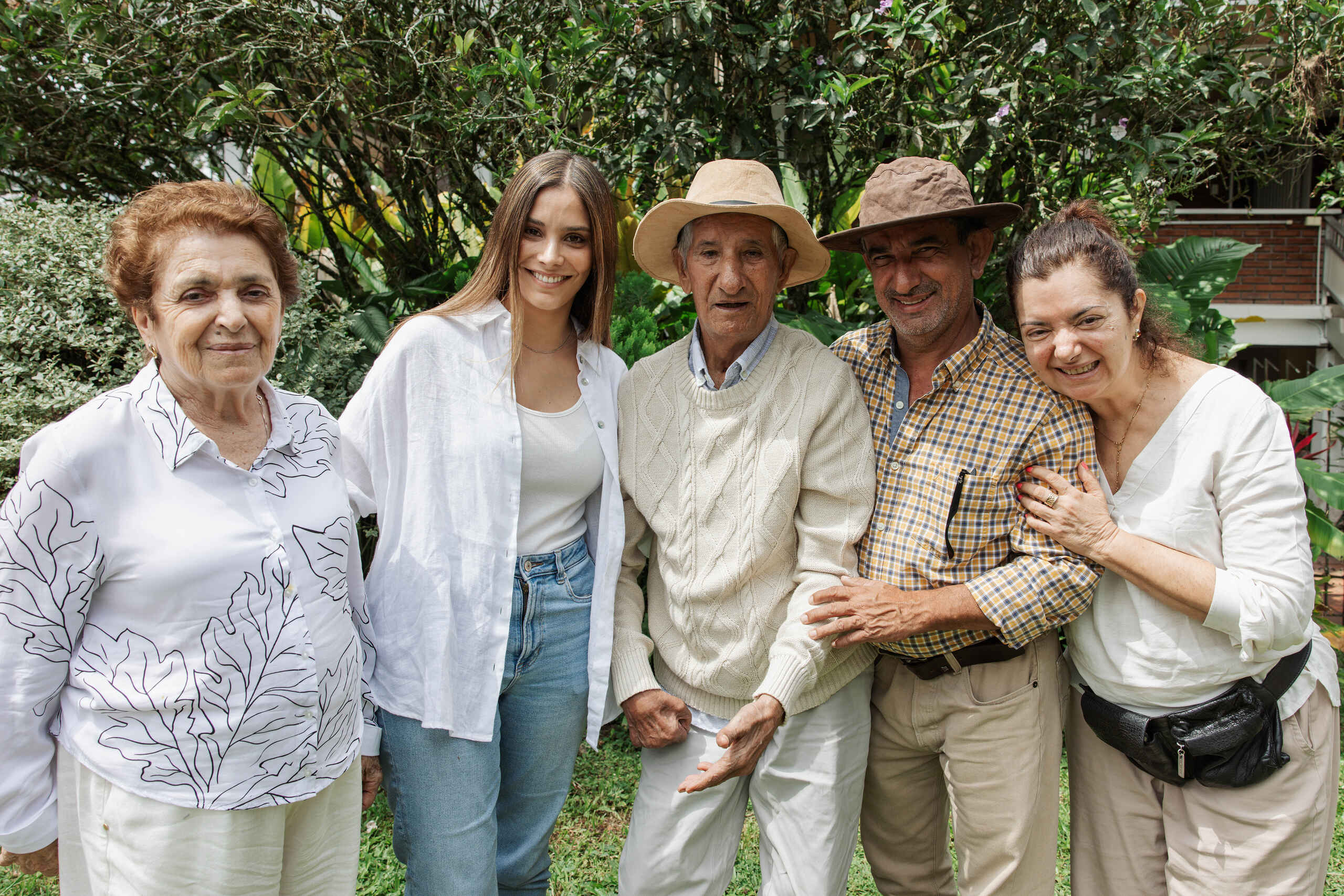 Five people smiling together in a garden setting, representing a farming family in Colombia