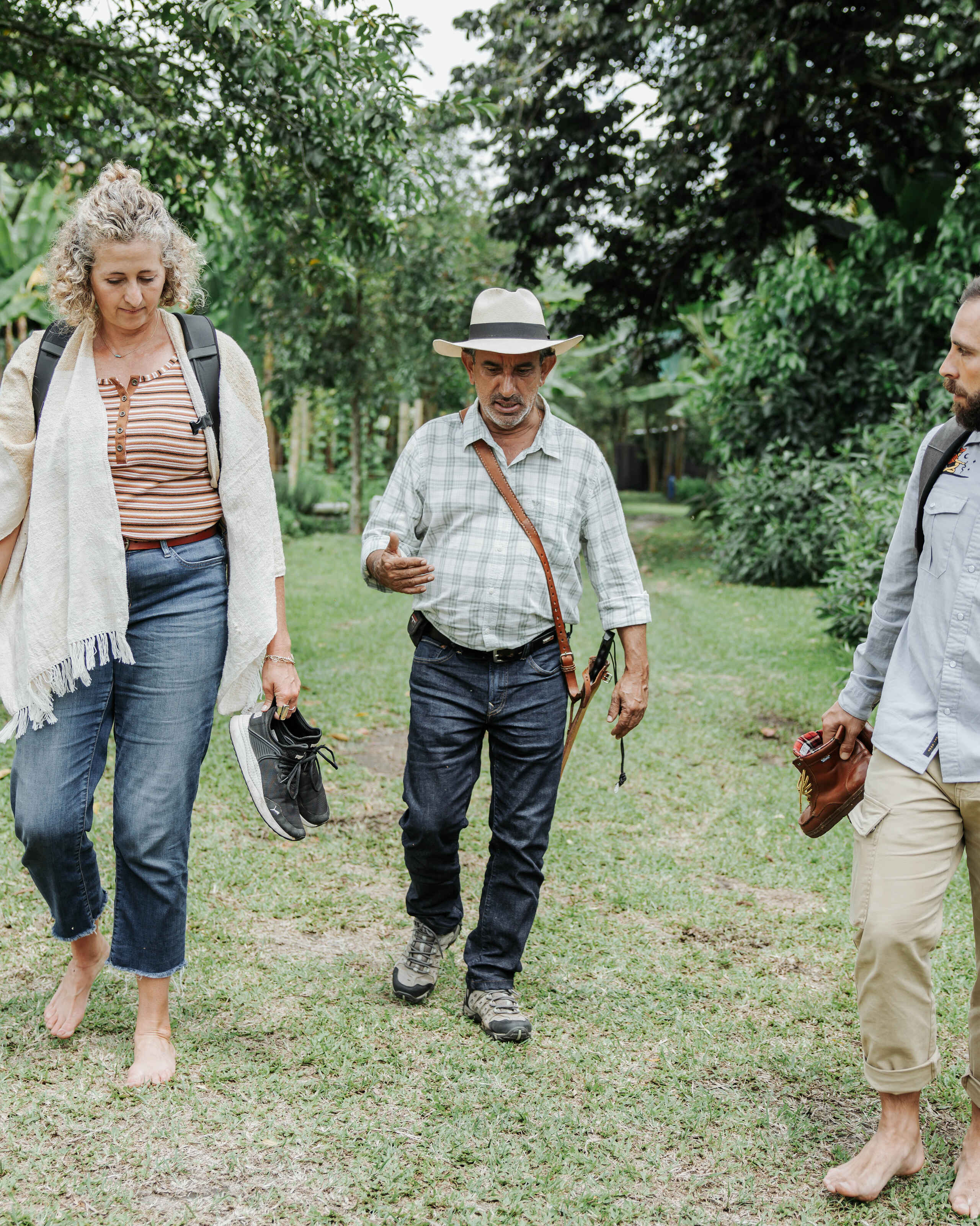 Three people walking together through a lush garden in Colombia discussing regenerative farming practices