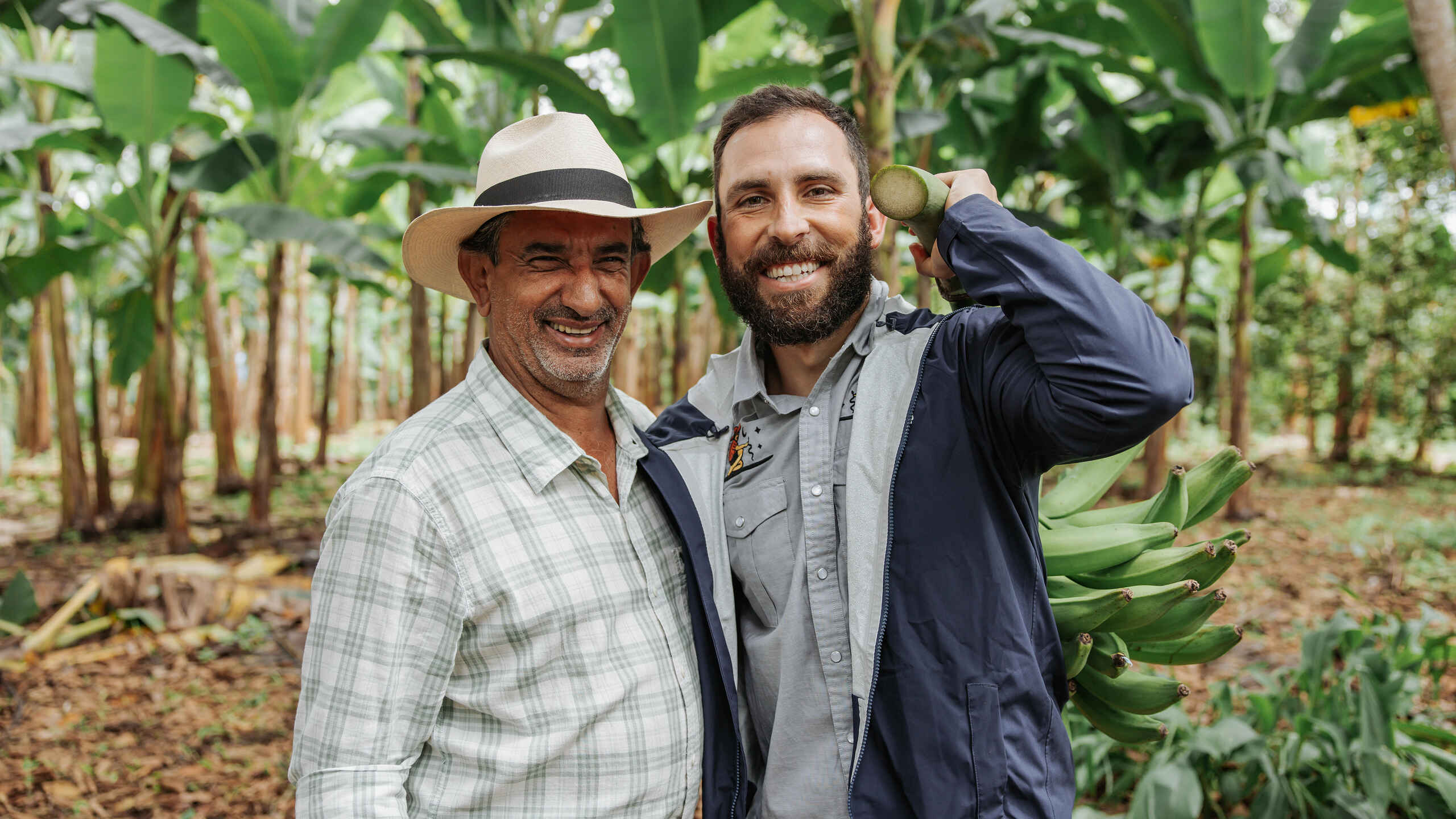 Two farmers smile together in a banana plantation in Colombia