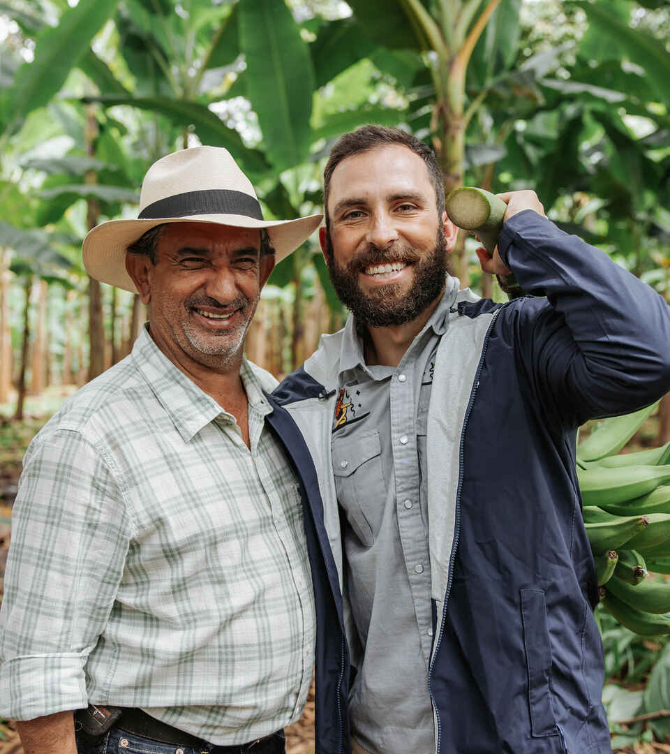 Two farmers smile together in a banana plantation in Colombia