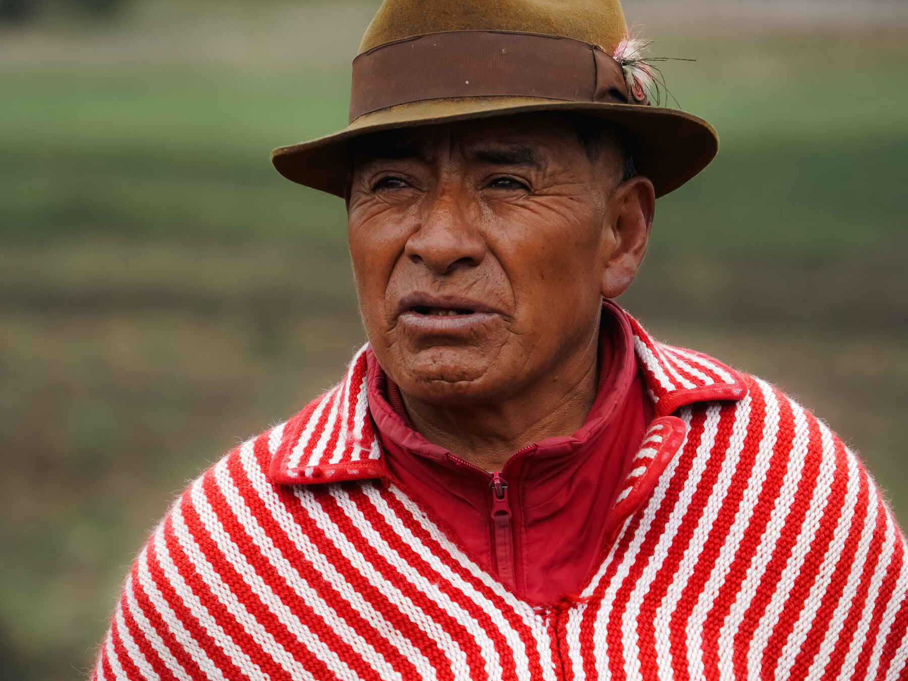 Agricultor ind&iacute;gena en los Andes ecuatorianos vistiendo ropa tradicional roja y blanca a rayas y un sombrero color tostado