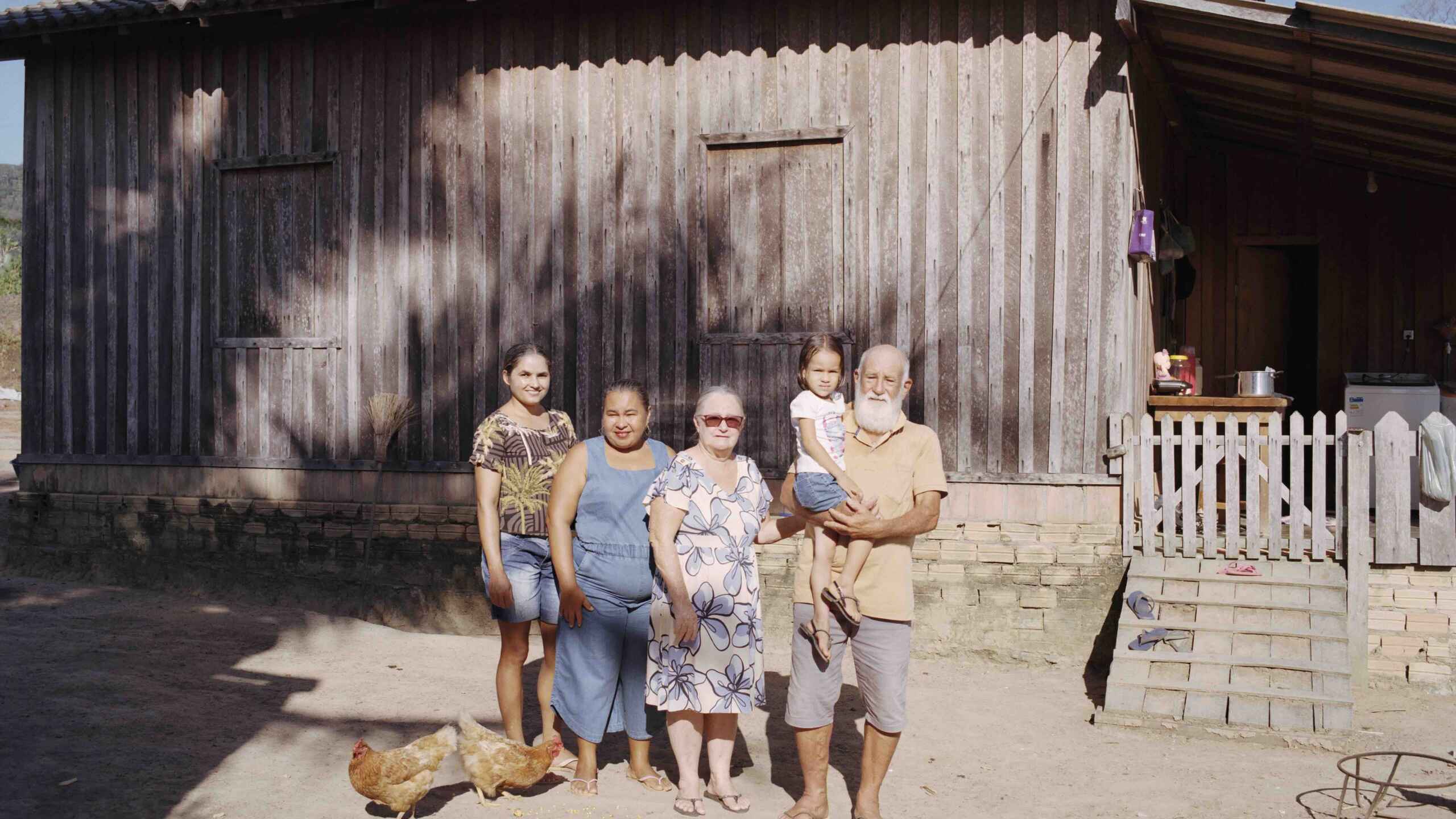A multigenerational family stands together outside their modest home in rural Brazil