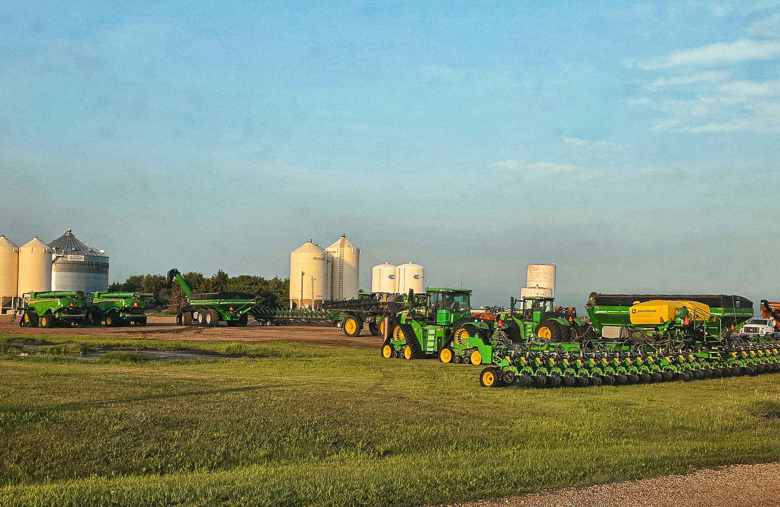 John Deere farming equipment and grain storage silos lined up in an agricultural operation