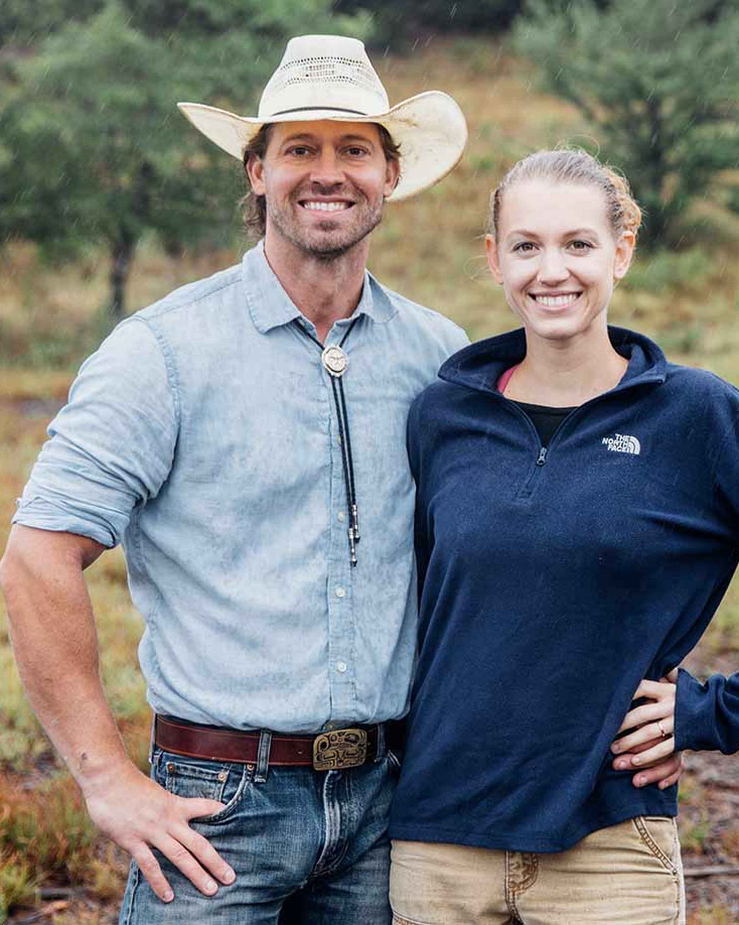 Tina and Orion Weldon smiling together outdoors with forested hills in the background
