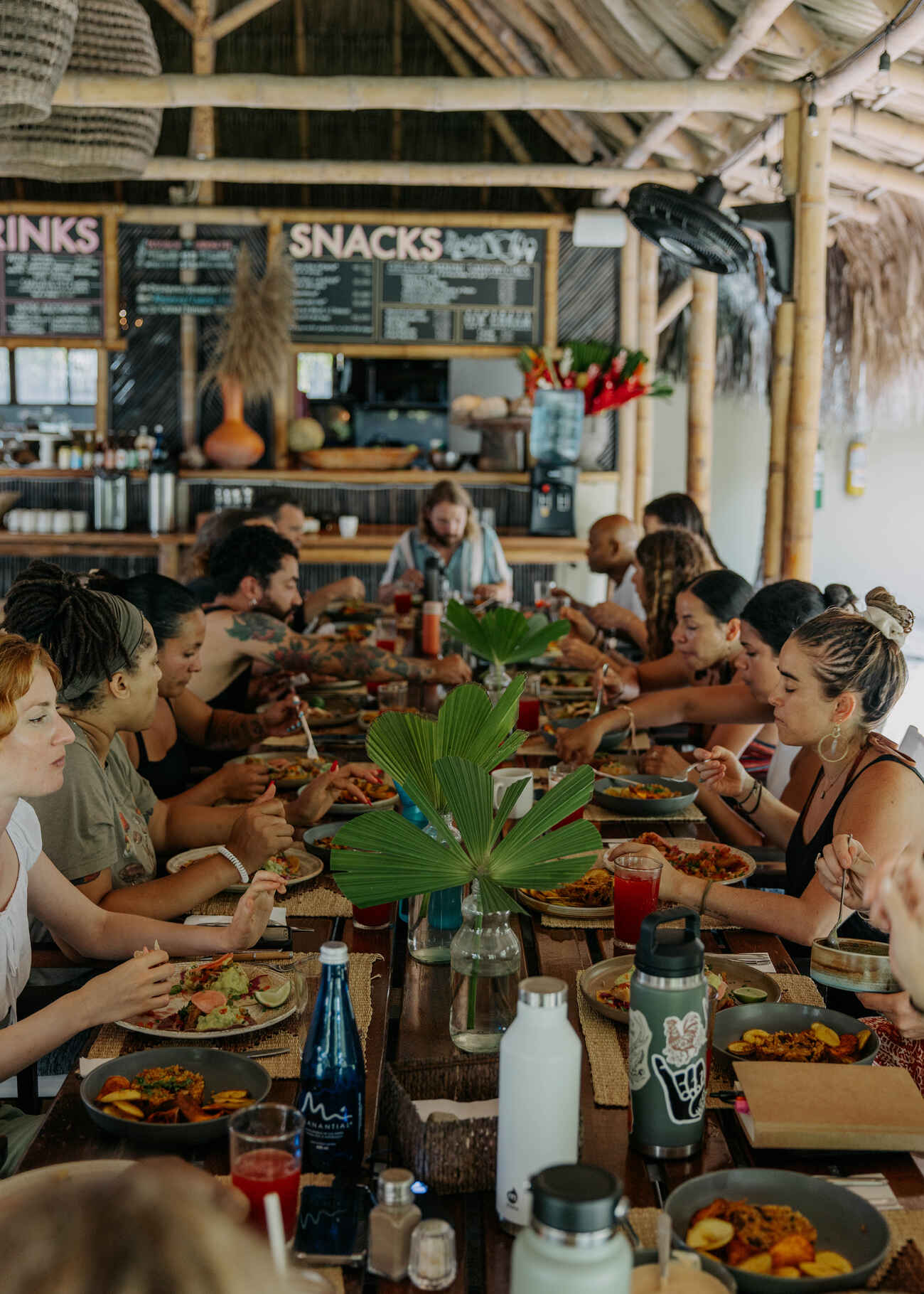 A diverse group of people sharing a meal together at a long wooden table in a rustic communal dining space